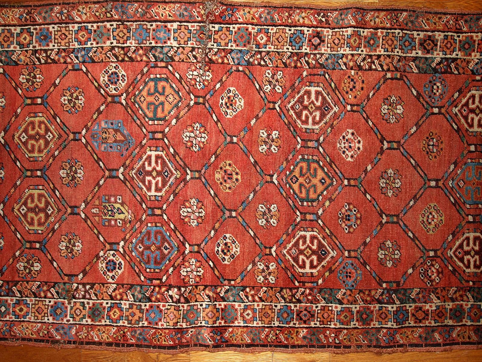Antique handmade Kurdish runner in bright red color. The rug has one cut on the side and damaged corner with several small holes. Measures: 3.2' x 12.2' (97cm x 371cm).