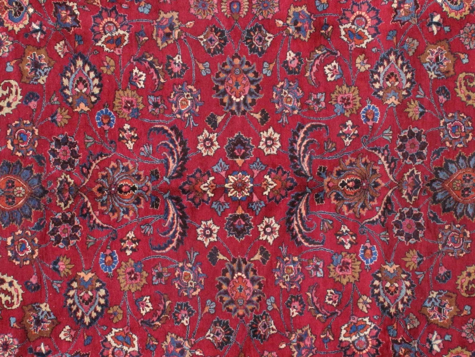 Antique Mashad style rug in original good condition. The field of the rug is in red shade with floral design and navy blue border. Measures: 8.7' x 11' (265 cm x 335 cm).