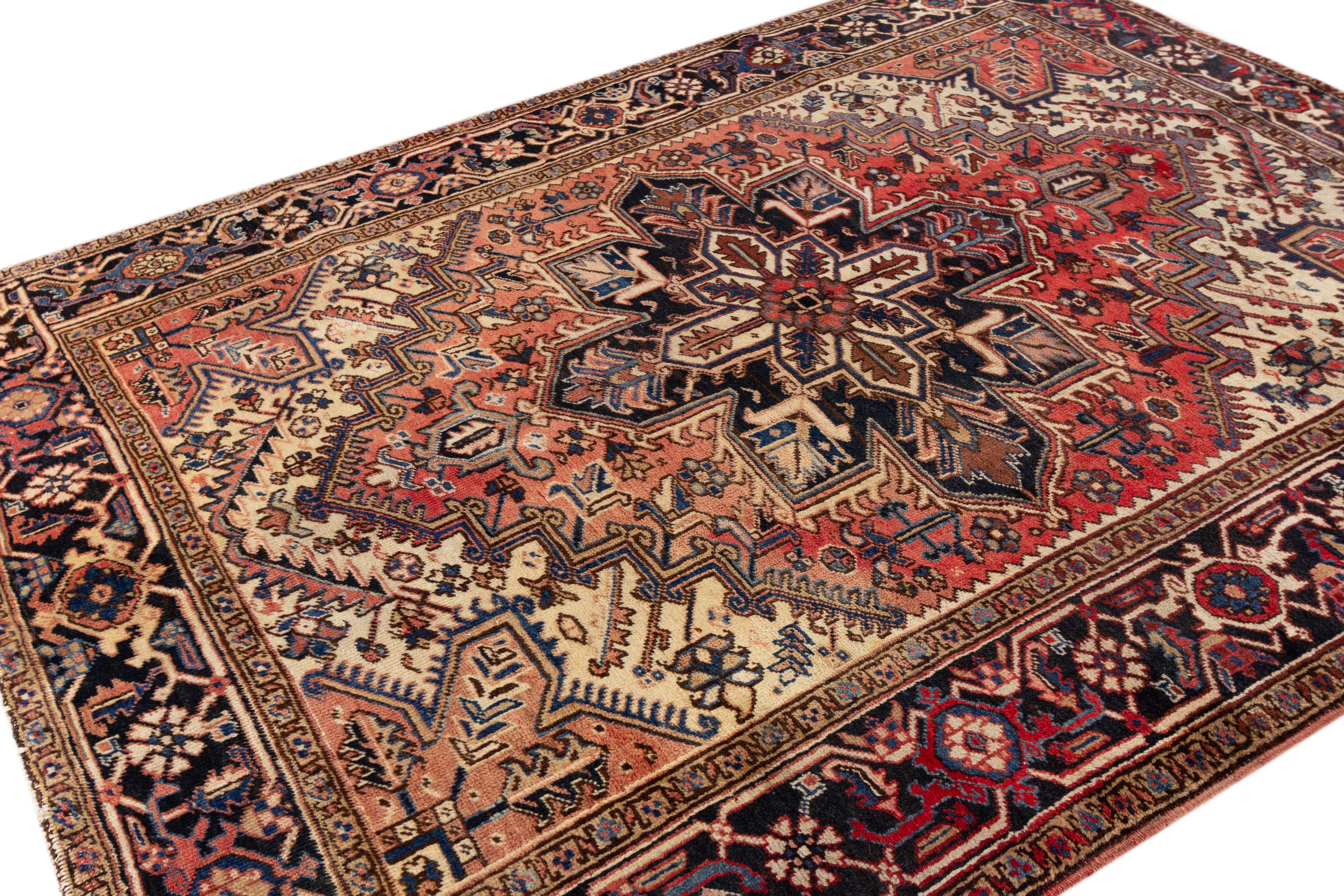 This antique Heriz rug with hand-knotted wool and a remarkable medallion design. The intricate floral motifs in shades of blue and brown, accentuating the soft red field, lend an alluring touch, making it a splendid work of Persian artistry.

This