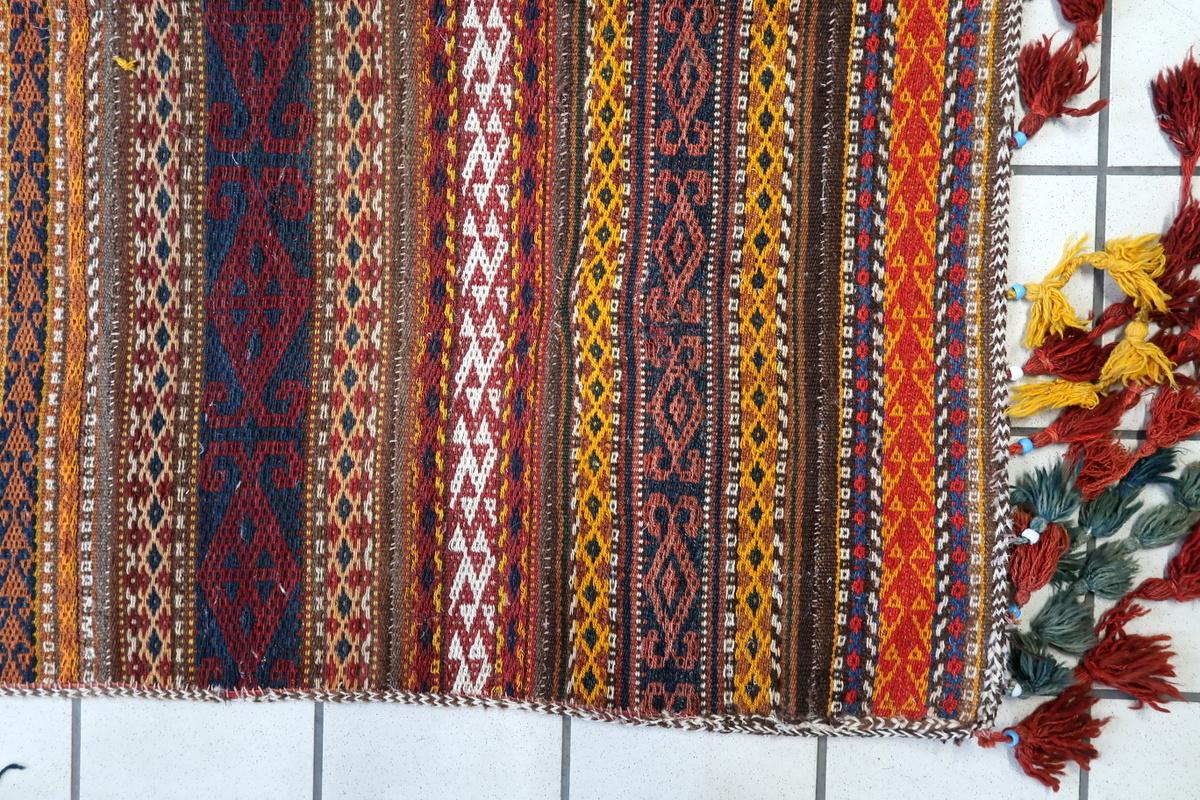 Ce Kilim berbère marocain ancien, fabriqué dans les années 1930, est un exemple étonnant de tissage tribal nord-africain. Fabriqué à la main avec 100 % de laine, ce tapis tissé à plat présente un éventail vibrant de teintures naturelles, notamment