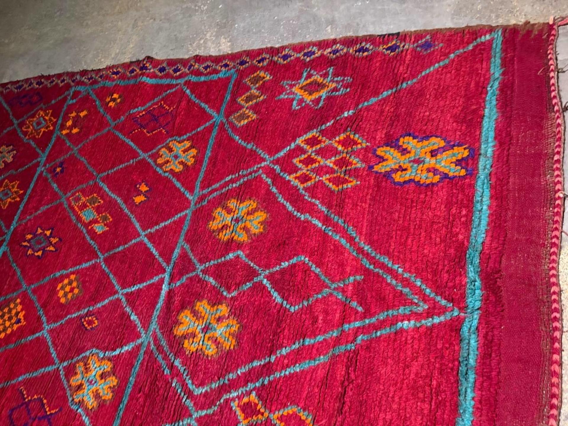 Questo imponente tappeto berbero marocchino antico, tessuto a mano nelle montagne dell'Atlante intorno agli anni '20, offre una dichiarazione grafica audace con colori e texture eccezionali. A differenza degli stili minimalisti di Beni Ourain,