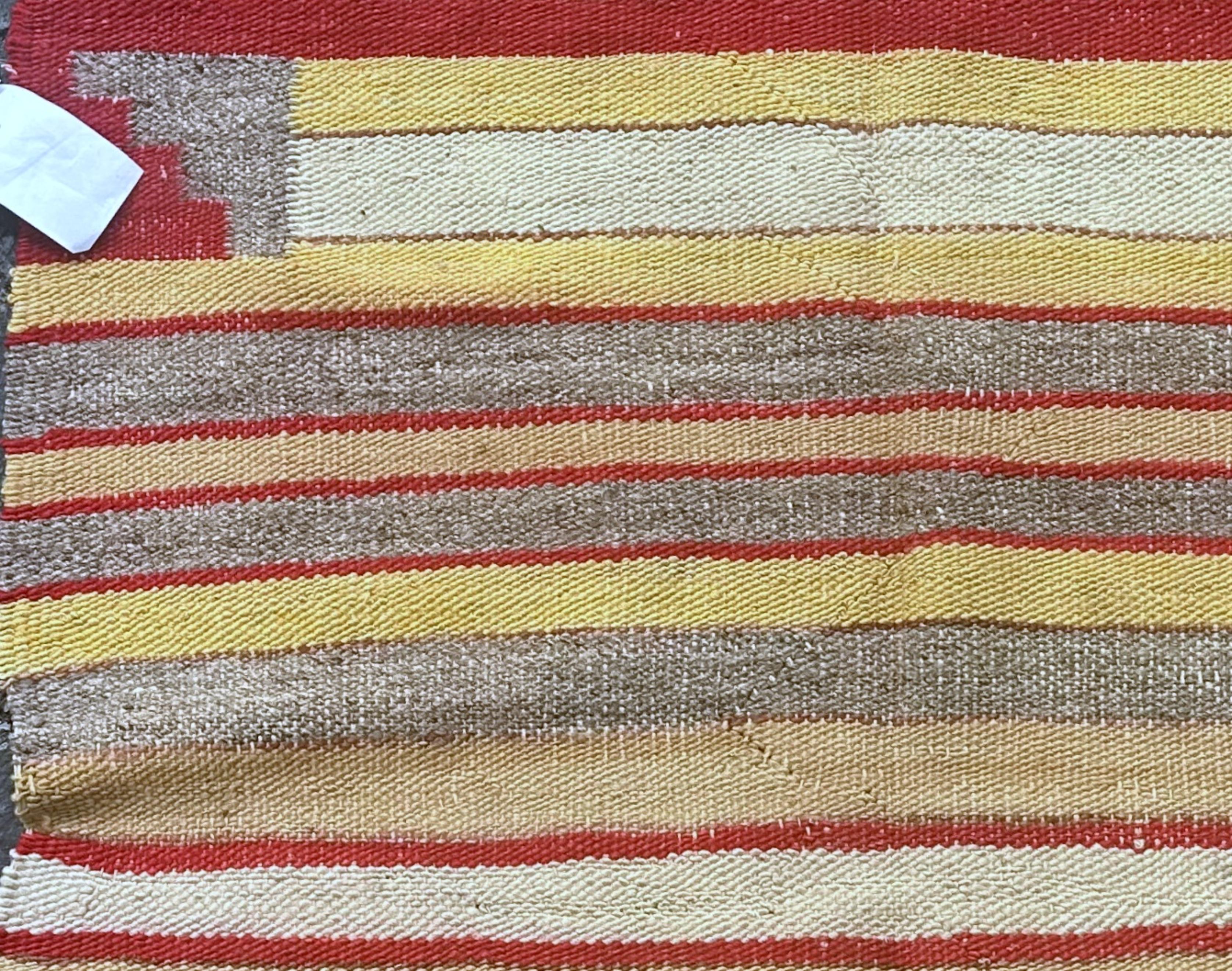 Ce charmant tapis ancien en laine Navajo, fabriqué à la main et datant des années 1900, est un témoignage de l'artisanat traditionnel et de l'art. Mesurant 2,2 pi x 2,5 pi (67 cm x 76 cm), il présente des rayures horizontales dans des tons chauds de
