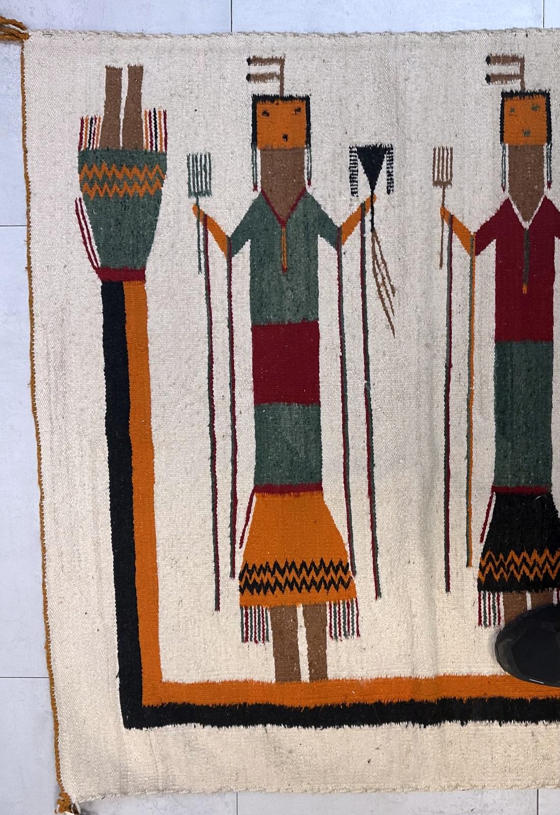 Questo tappeto Navajo fatto a mano è un tesoro da collezione, un pezzo d'arte popolare americana davvero unico e avvincente. Tessuto con una ricca lana filata a mano, presenta un sorprendente disegno pittorico con una serie di figure spirituali o