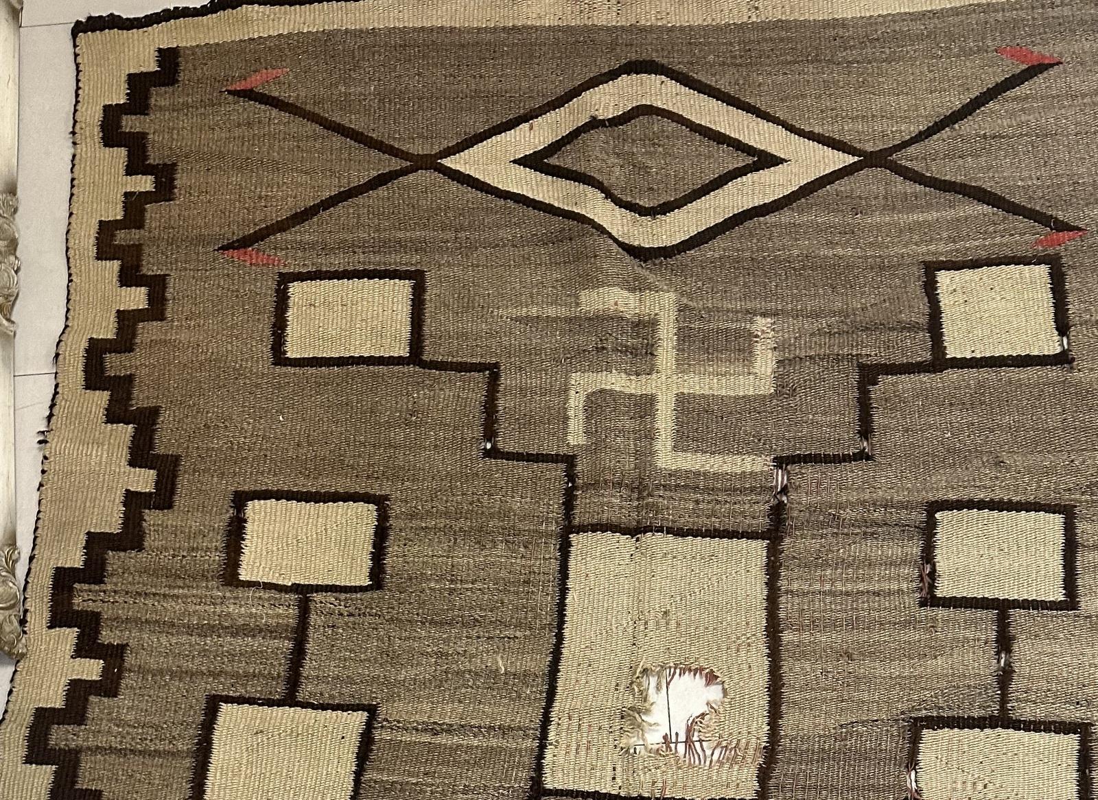 Ce tapis Navajo ancien, fait à la main et mesurant 122 cm sur 155 cm, est un magnifique exemple de l'artisanat traditionnel du début des années 1900. Fabriqué entièrement en laine, ce magnifique tapis présente des motifs complexes et une riche