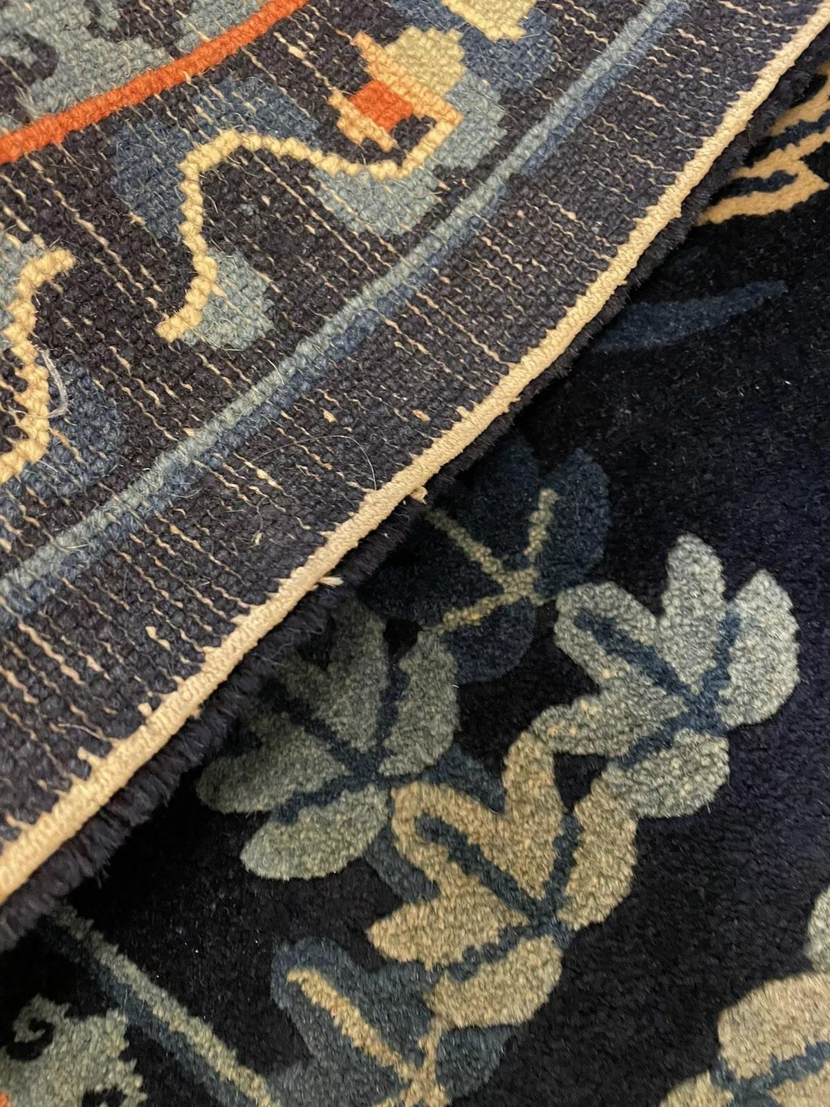 Retournez dans l'histoire avec cet exquis tapis ancien de Pékin, fait à la main et datant des années 1900. Ce chef-d'œuvre de laine au tissage complexe mesure environ 57 cm x 110 cm (1,87 pi x 3,61 pi), ce qui en fait une pièce d'accentuation