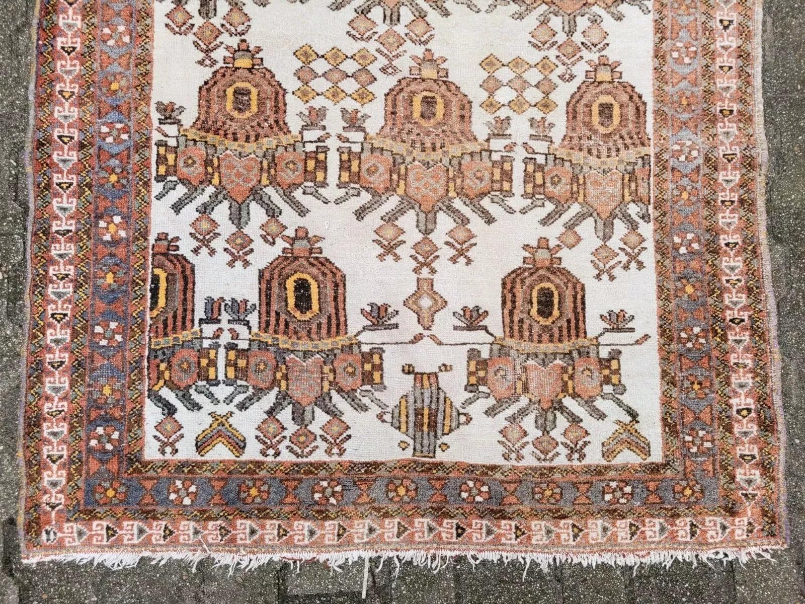 Ce charmant tapis Hamadan ancien, fabriqué à la main au Moyen-Orient dans les années 1930, présente un remarquable motif tribal avec des médaillons symboliques répétés sur un doux champ ivoire. Chaque motif, riche en caractère et en héritage,