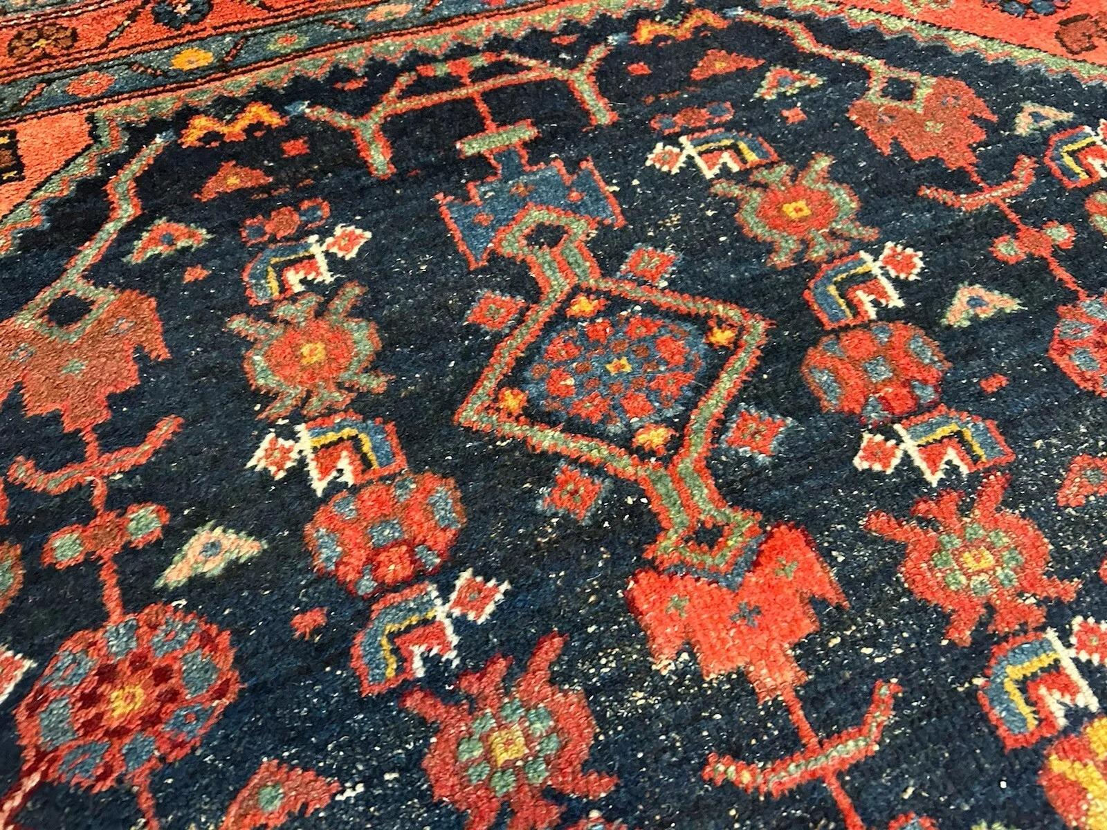 This antique Persian Hamadan rug, dating back to the 1920s, is a stunning representation of Persian craftsmanship. Woven from fine wool, it features bold geometric patterns and rich, earthy tones, characteristic of the Hamadan weaving