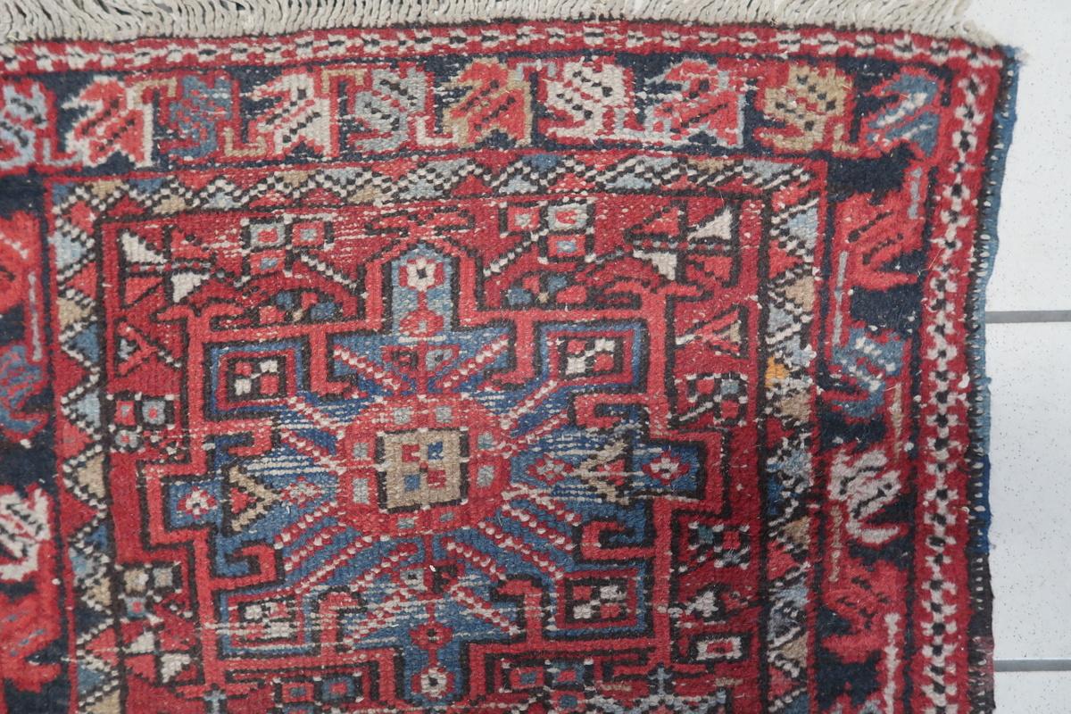 Questo antico tappeto persiano Karajeh, risalente agli anni '10 del Novecento, è un notevole esempio di artigianato tribale tradizionale. Tessuto con lana di alta qualità, presenta un sorprendente disegno geometrico a medaglione in ricchi rossi, blu