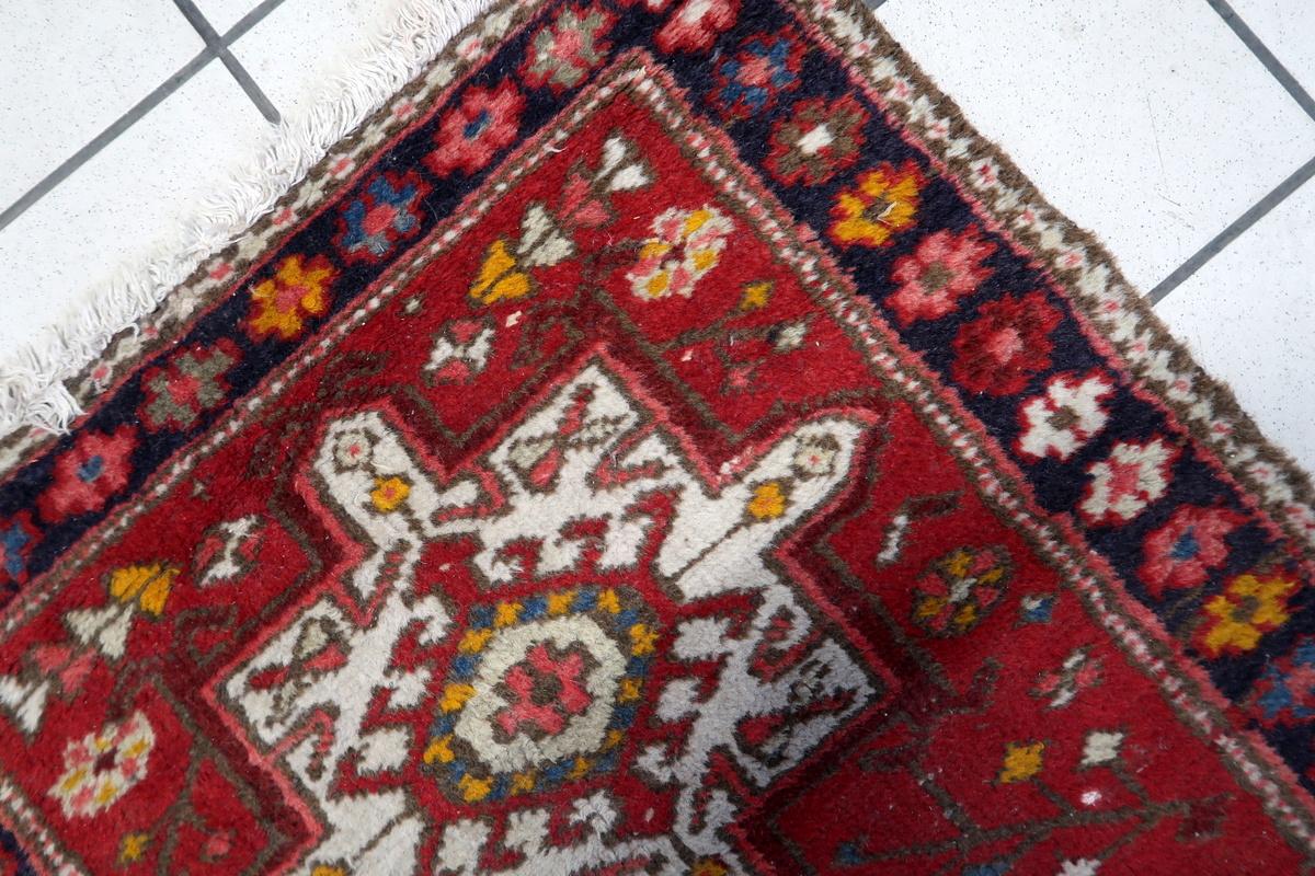 Cet ancien tapis persan Karajeh des années 1930 est un magnifique exemple de l'artisanat traditionnel tissé à la main. Présentant un motif géométrique audacieux sur un riche champ rouge, cette pièce met en valeur trois médaillons centraux aux
