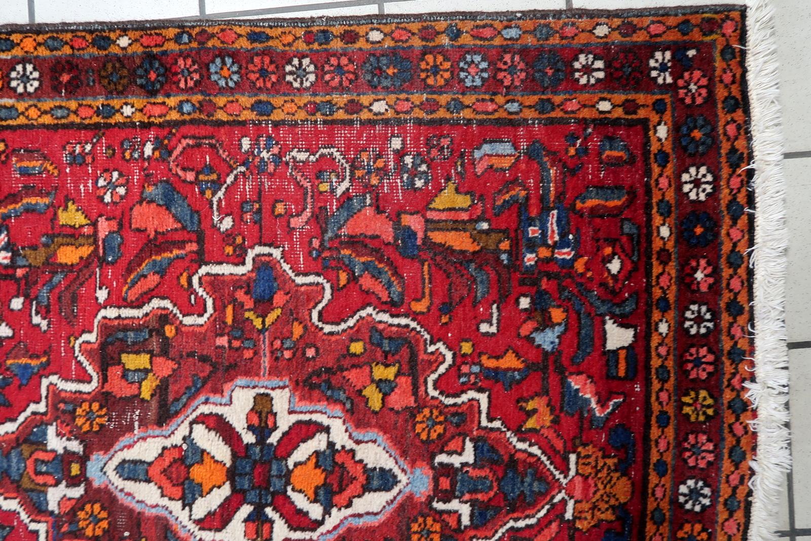 Questo antico tappeto persiano Karajeh fatto a mano e risalente agli anni '20 presenta un sorprendente disegno geometrico tribale con una palette di colori vivaci. Tessuto con lana di alta qualità, presenta un ricco sfondo rosso, accentuato da blu