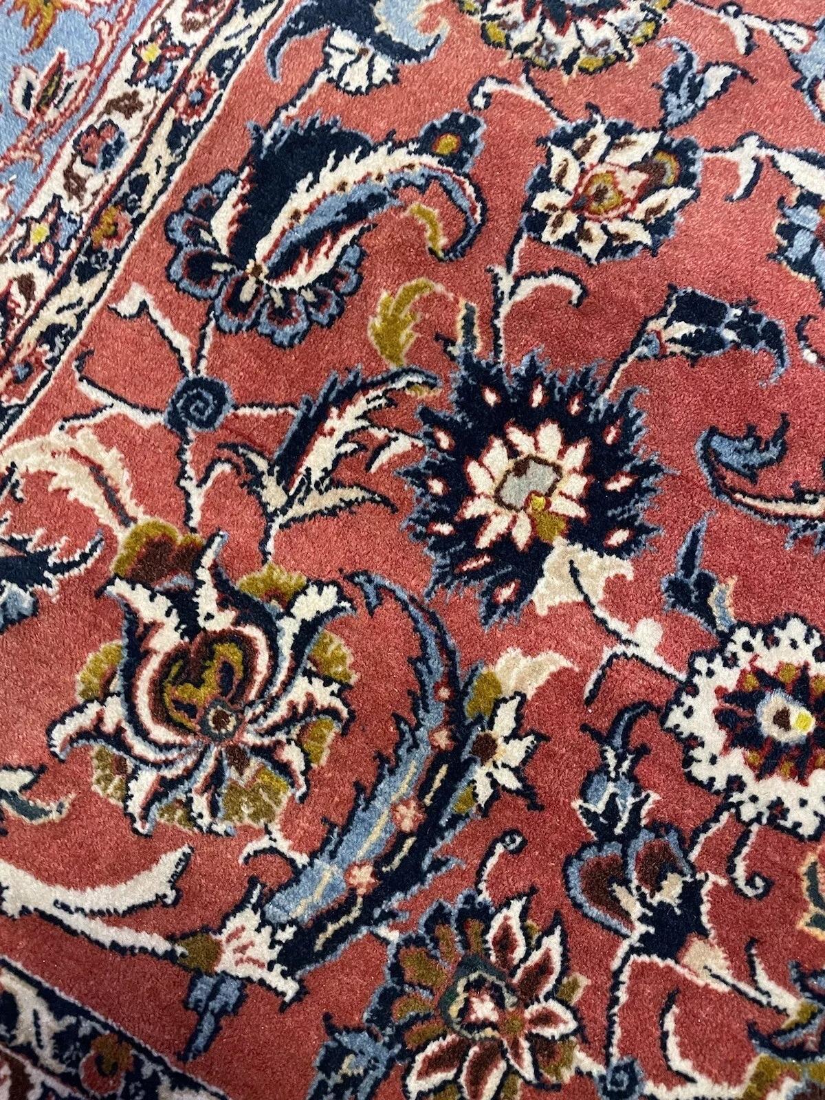 Dieser exquisite, handgefertigte antike persische Kashan-Teppich aus den 1920er Jahren zeigt die zeitlose Kunstfertigkeit und das handwerkliche Können der persischen Weberei. Der aus Wolle gefertigte Teppich weist komplizierte Muster auf, die die
