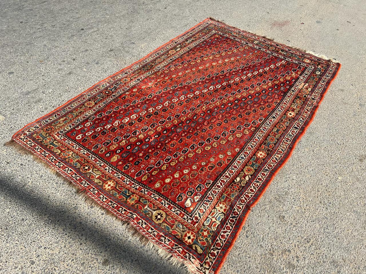 Entrez dans l'allure intemporelle de l'artisanat persan avec ce tapis persan ancien Khamseh fait à la main et datant des années 1900. Mesurant 5,1 pieds de largeur et 8,5 pieds de longueur (155cm x 259cm), ce tapis captivant présente une palette de