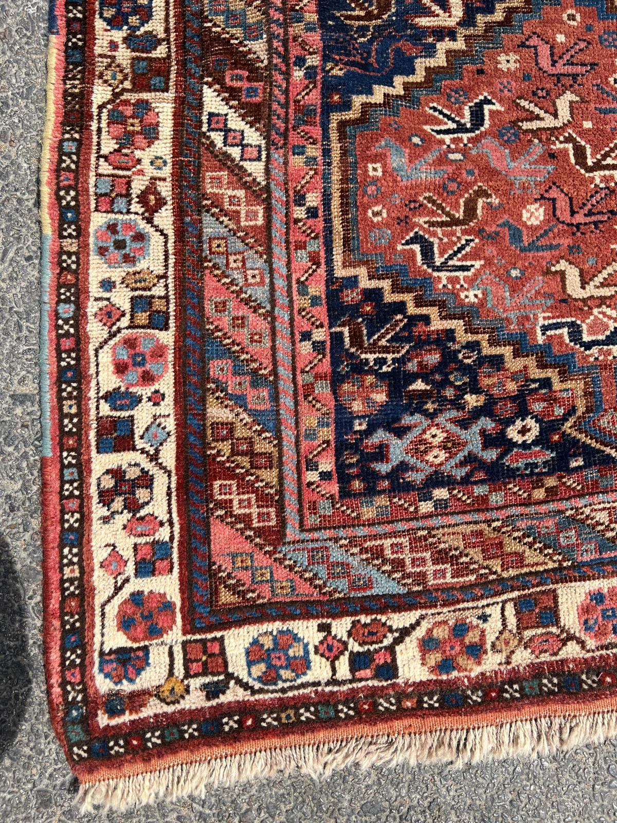 Cet exceptionnel tapis persan Khamseh des années 1880 témoigne de l'art magistral du tissage tribal. Son design captivant présente une série de grands médaillons hexagonaux interconnectés, chacun rempli d'une riche tapisserie de motifs complexes.