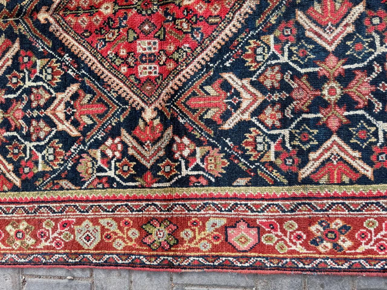 Dieser auffällige antike persische Mahal-Teppich (frühes 20. Jahrhundert) bietet eine faszinierende Mischung aus anspruchsvoller persischer Kunstfertigkeit und kühner Stammesgeometrie. Der aus strapazierfähiger, hochwertiger Wolle handgeknüpfte