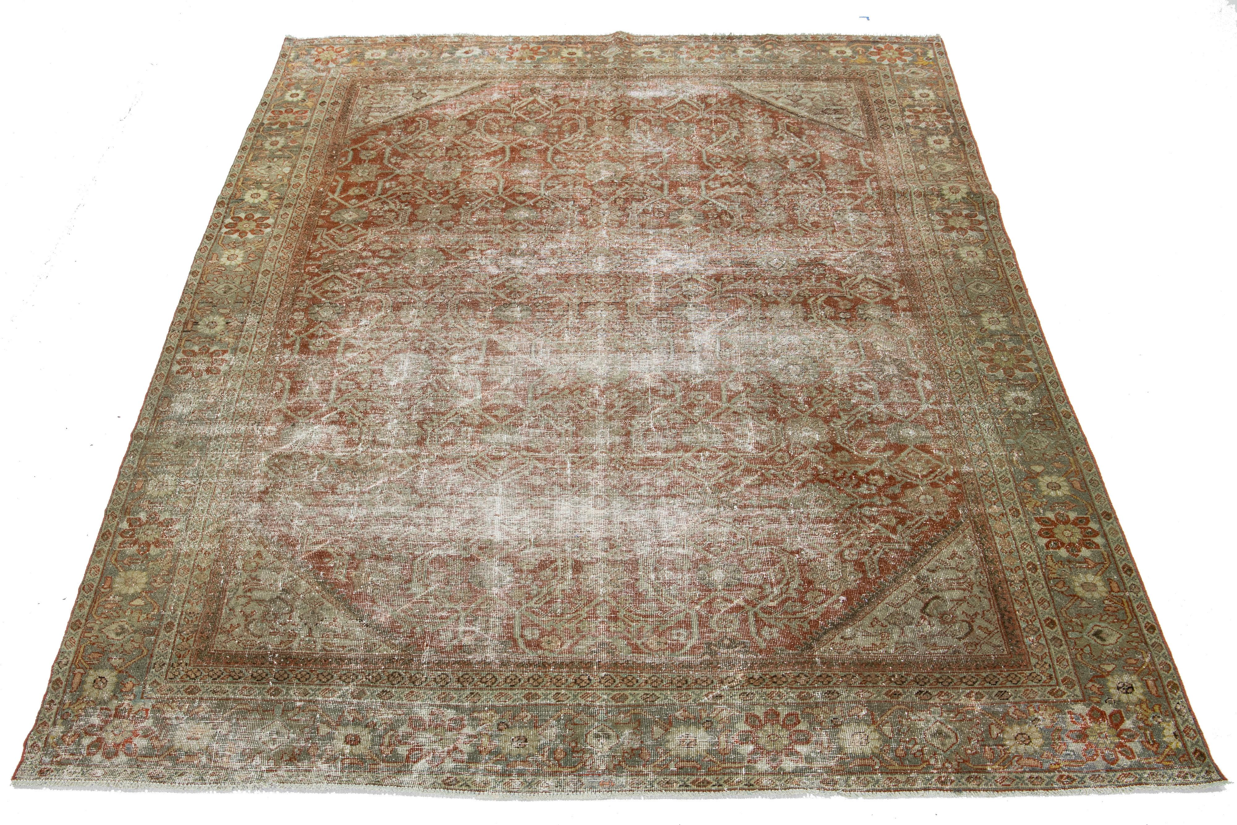 A hand-knotted wool antique Mahal rug features an all-over design with blue, brown, and beige accents on a rust color field.

This rug measures 8'2