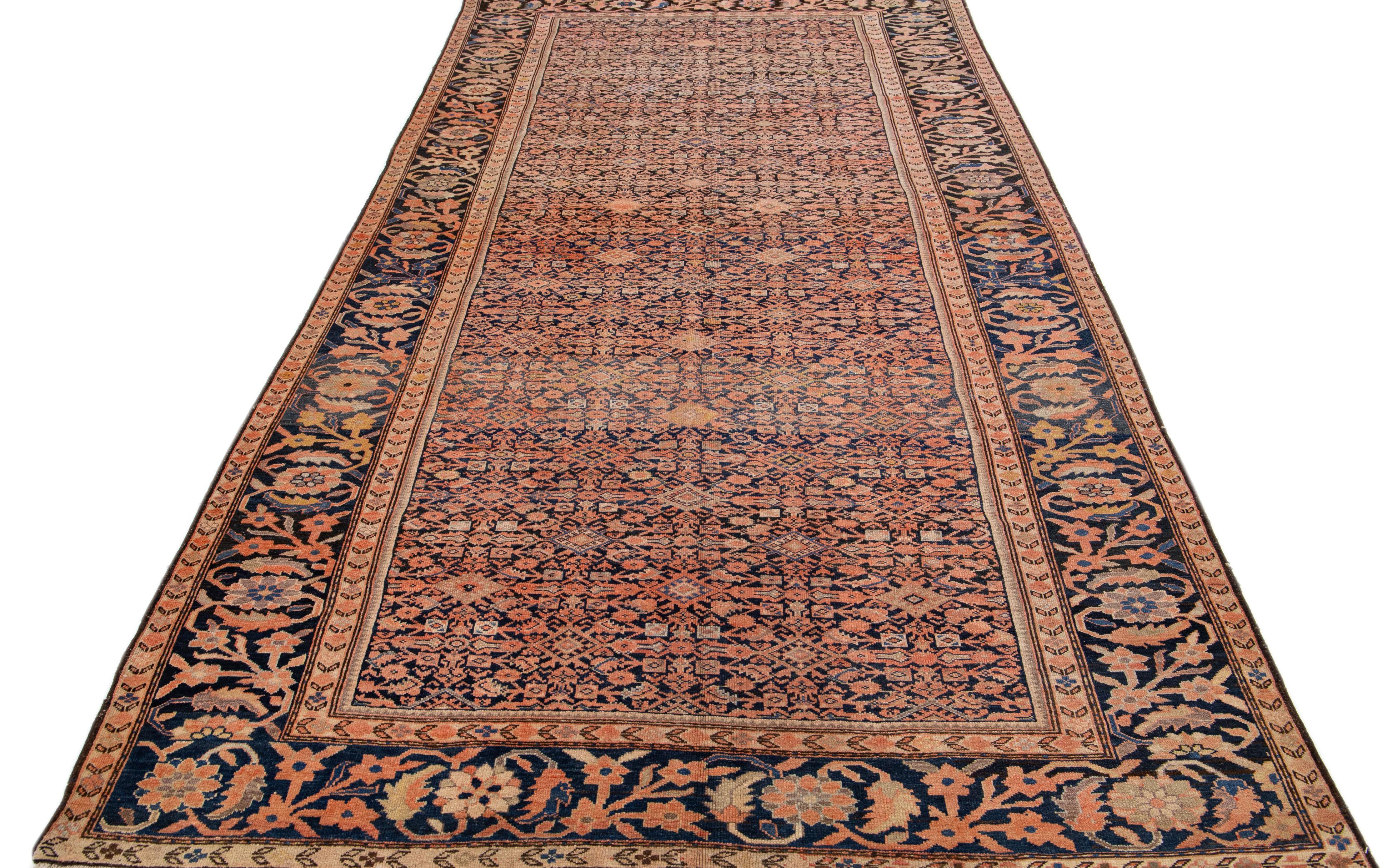 A beautiful Antique Malayer hand-knotted wool rug with a dark blue field. This Persian rug has peach and beige accents in an all-over floral design.

This rug measures 6'9
