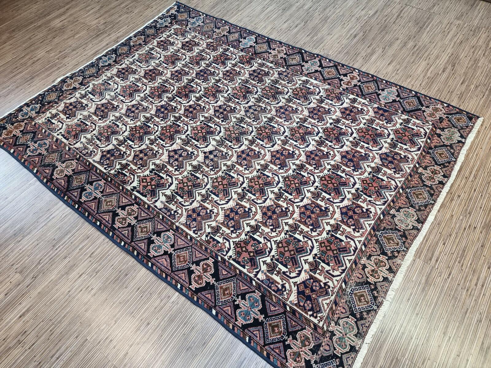 Immergez votre espace dans l'art du Moyen-Orient avec notre tapis Afshar ancien de style persan fait à la main. Fabriquée méticuleusement dans les années 1920, cette pièce mesure un généreux 5,3' x 6,9', offrant une large couverture pour votre