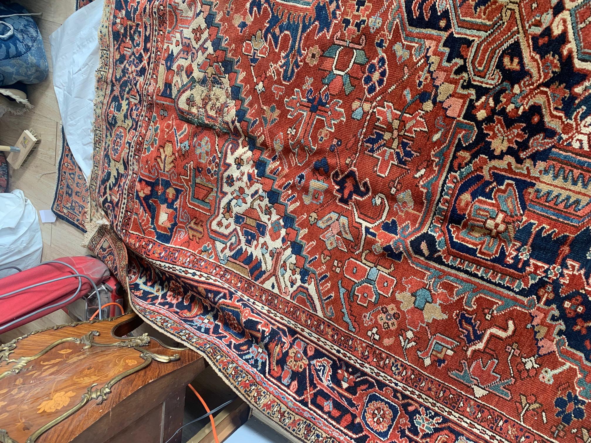 Introducing our Handmade Antique Persian Style Heriz Rug, a timeless piece measuring 9.4' x 12.5'. Crafted in the 1900s, this rug bears the charm of age with some wear that adds character and authenticity. Its traditional design features a prominent
