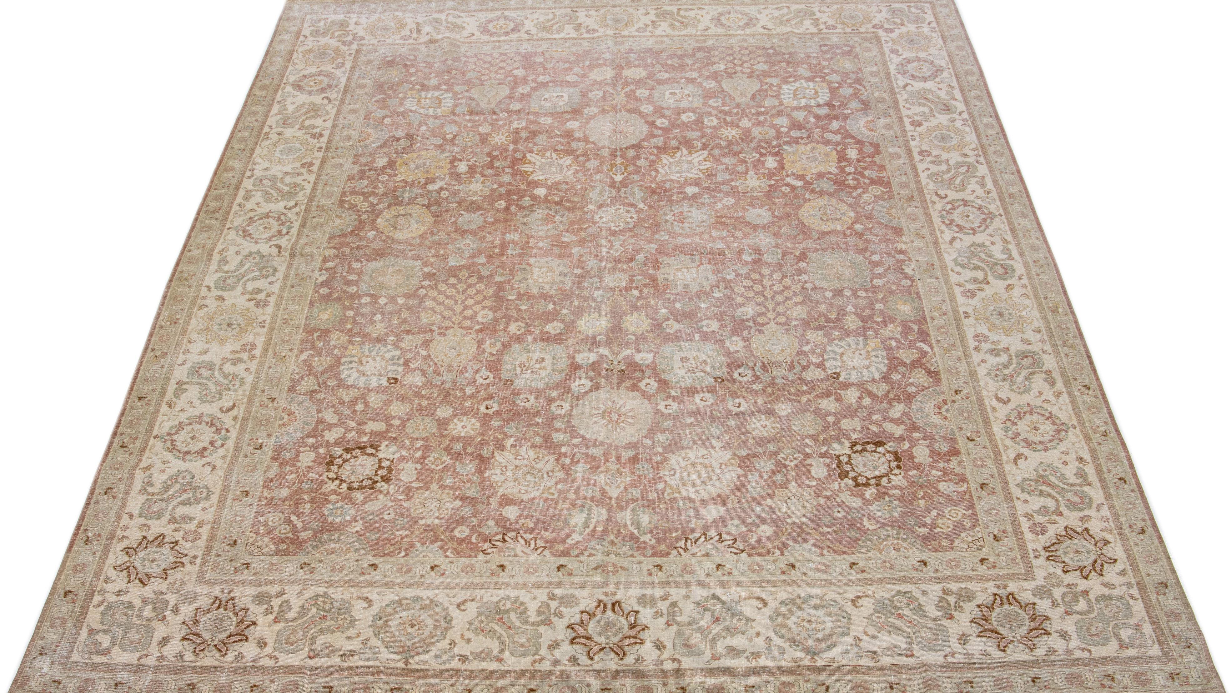 Beautiful antique Tabriz hand-knotted wool rug with a rust color field. This Persian rug has gray, green, and goldenrod accents in a gorgeous all-over floral design.

This rug measures: 9'9