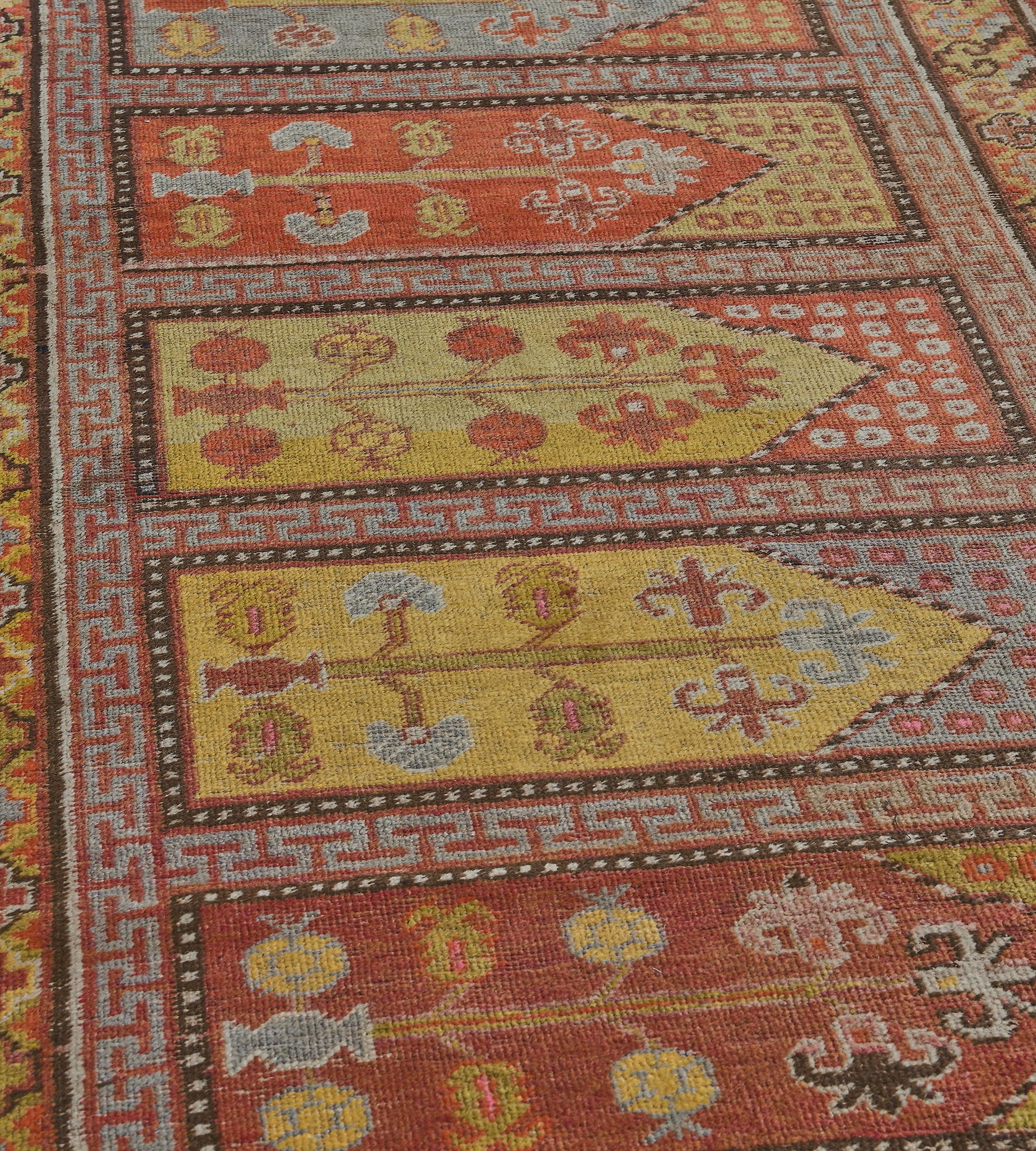 This antique Khotan Runner has a field with eight polychrome rectangular panels each with a prayer arch above with stylised dots the main field with angular floral stems surrounded by a narrow stripe containing steel-blue and burgundy-red