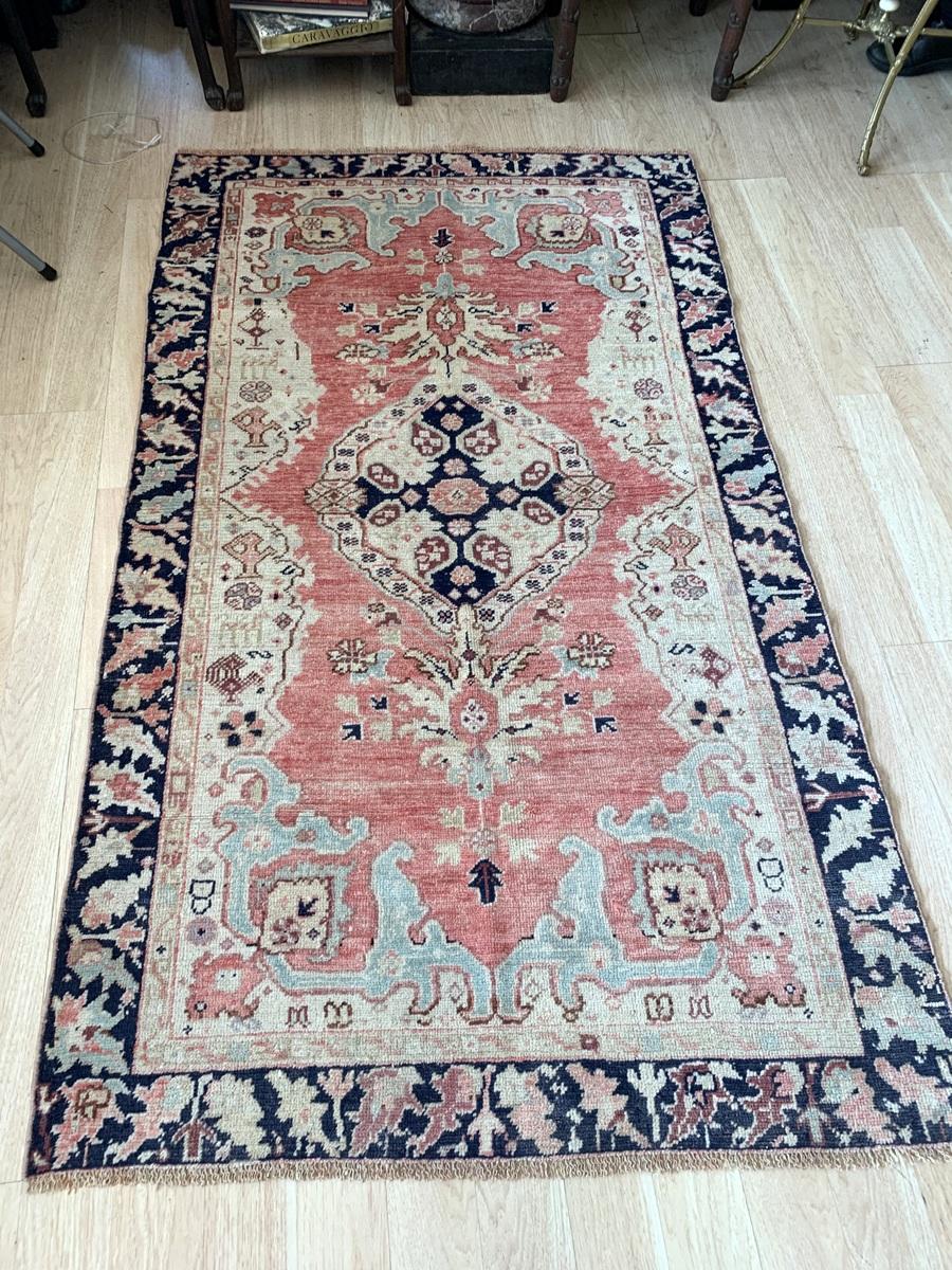 Ce tapis antique turc anatolien des années 1920, fait à la main, est un magnifique exemple de l'artisanat traditionnel. Il présente un médaillon magnifiquement détaillé et des motifs floraux dans une palette de couleurs chaudes et vintages. Les