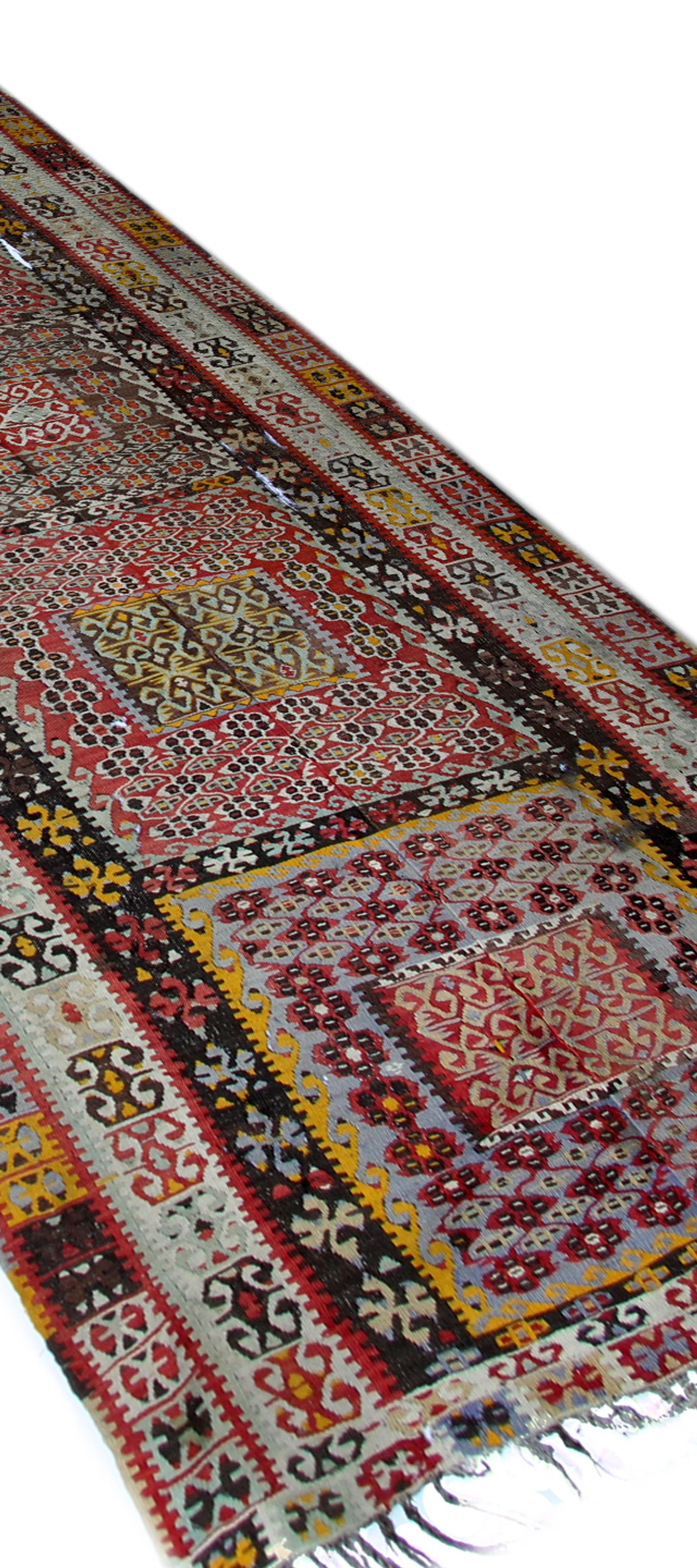 This highly decorative antique Turkish Kilim has been constructed using the finest handspun wool dyed in muted red, brown and ivory colours, using organic vegetable dyes. Featuring tribal motifs woven through the centre with a highly detailed border