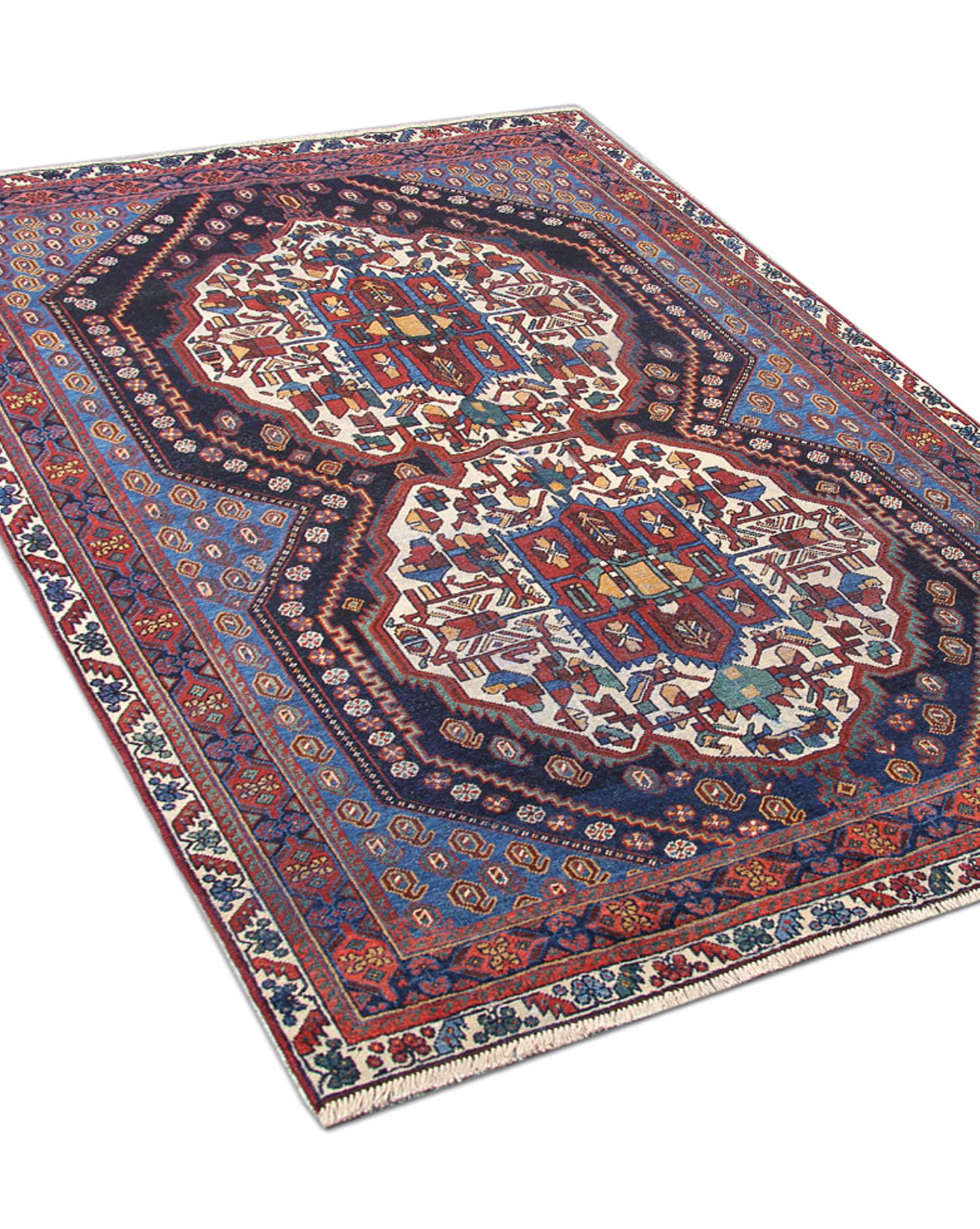 This traditional carpet handwoven area rug was constructed in the 1940s. It features two highly detailed central medallions woven on a deep blue field in accents of ivory blue and red. Handwoven with hand-spun wool, which was organically dyed using