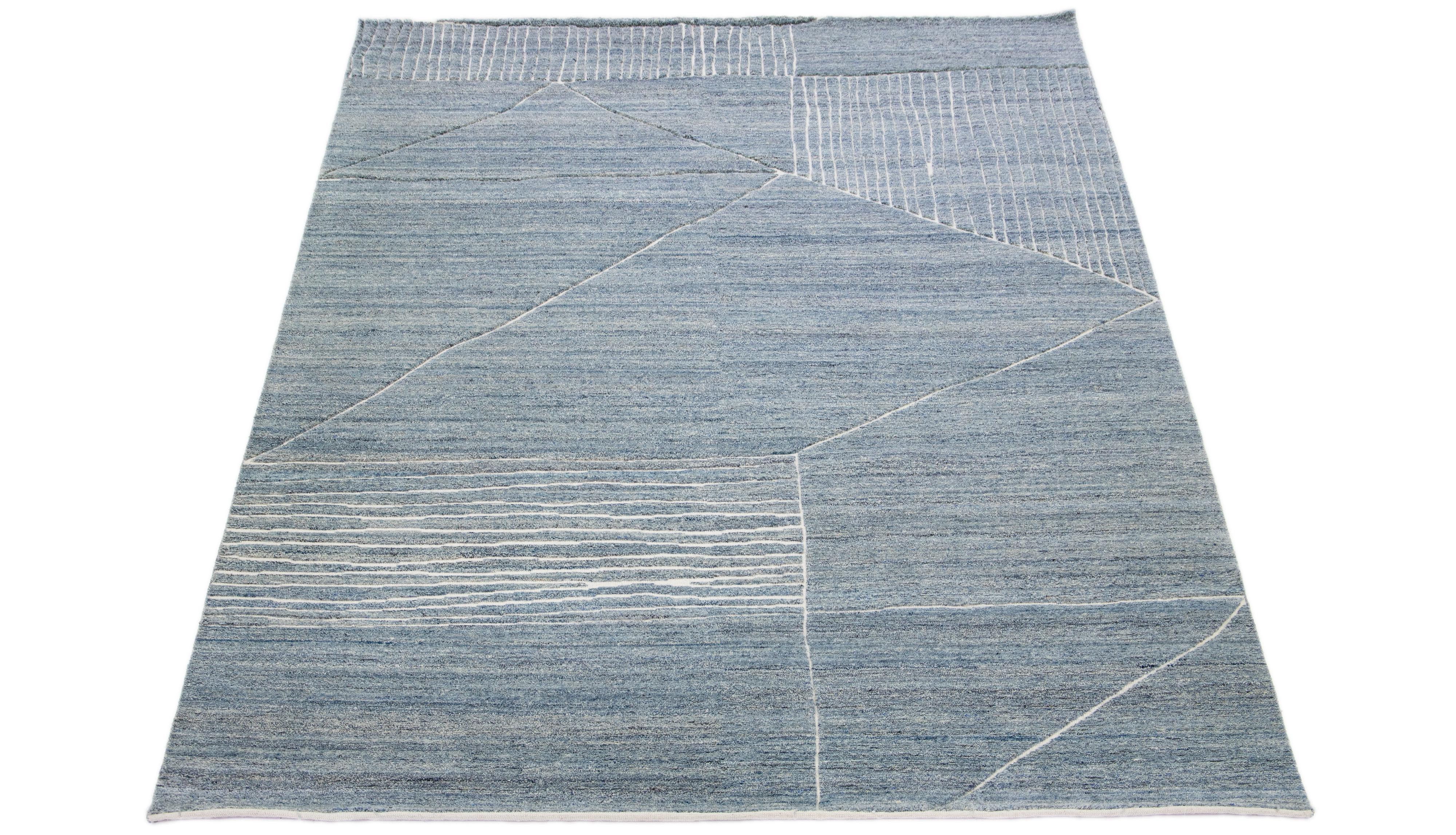 This luxurious wool rug features a timeless Moroccan pattern in a contemporary abstract Minimalist style, utilizing blue tones to create a sleek and modern look. It is crafted using traditional hand-knotting techniques, ensuring exceptional quality