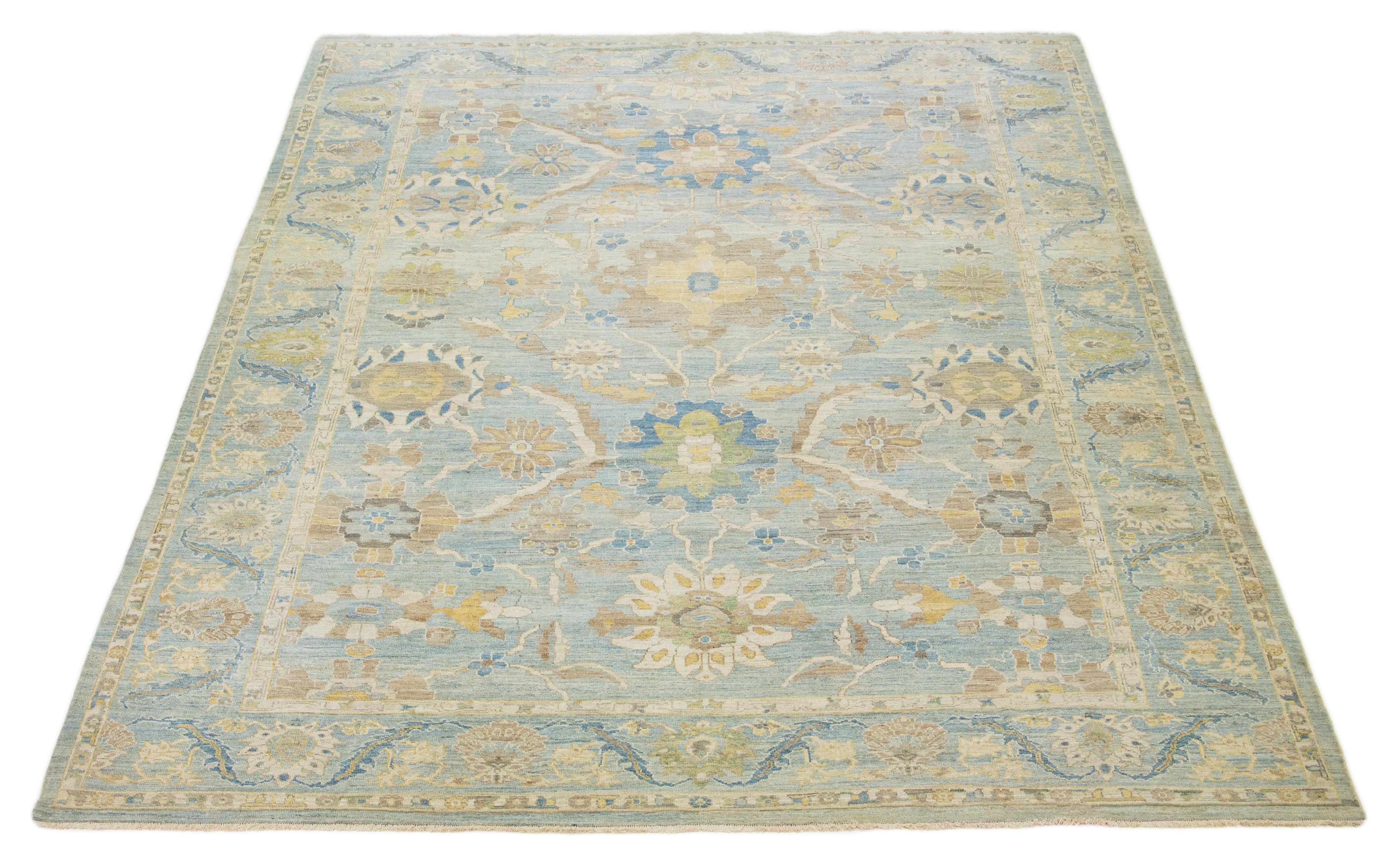 Questo tappeto in lana annodato a mano ha uno sfondo azzurro ornato da disegni gialli, beige, verdi e marroni all-over.

Questo tappeto misura 12'3'' x 15'6''.