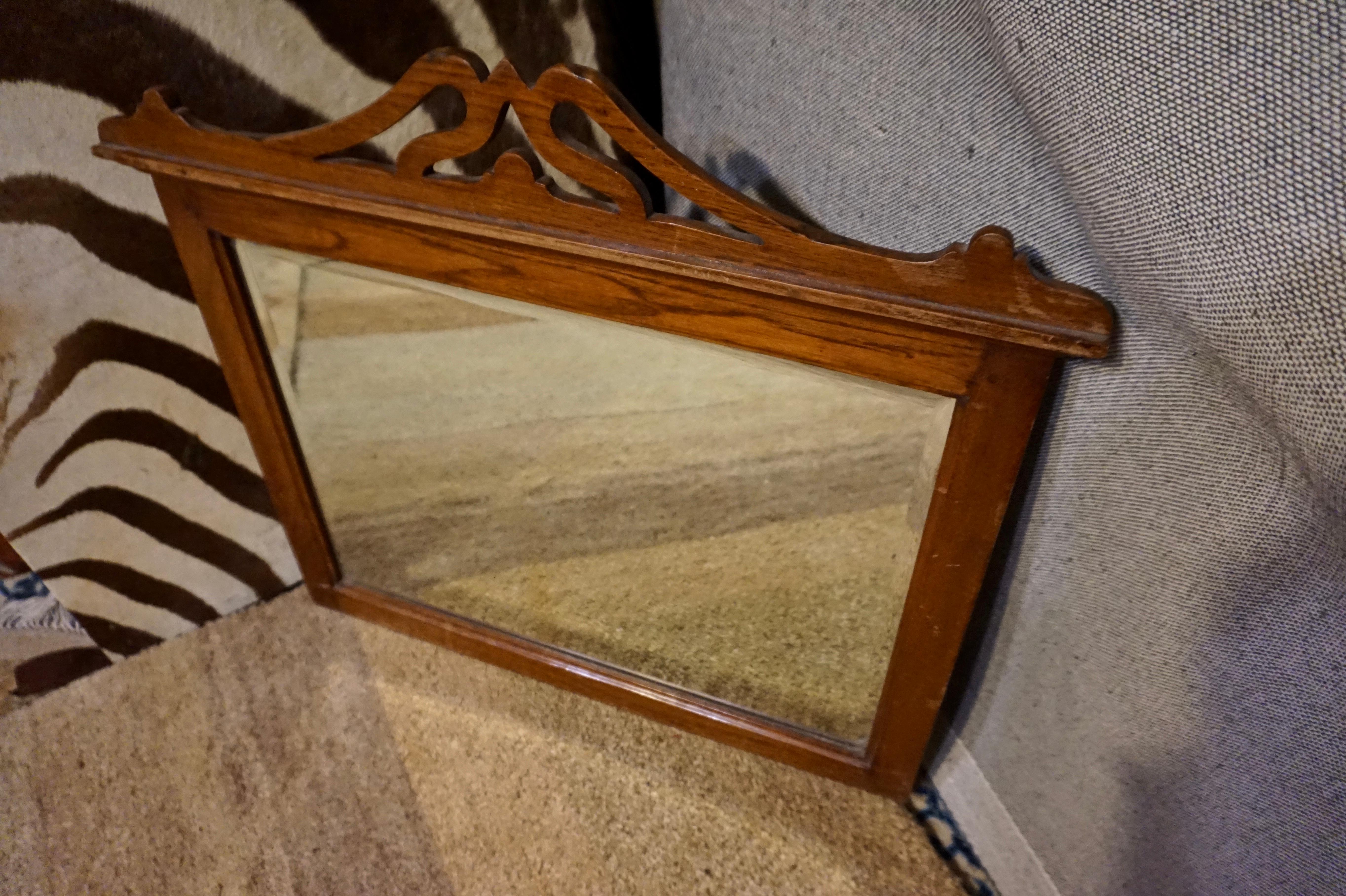 Hand carved Art Nouveau mirror with bevel glass. Scrolling motif meeting at the apex. Brass hardware indicates it was originally used on a pedestal. Presently being used as an over mantel (fireplace) mirror.