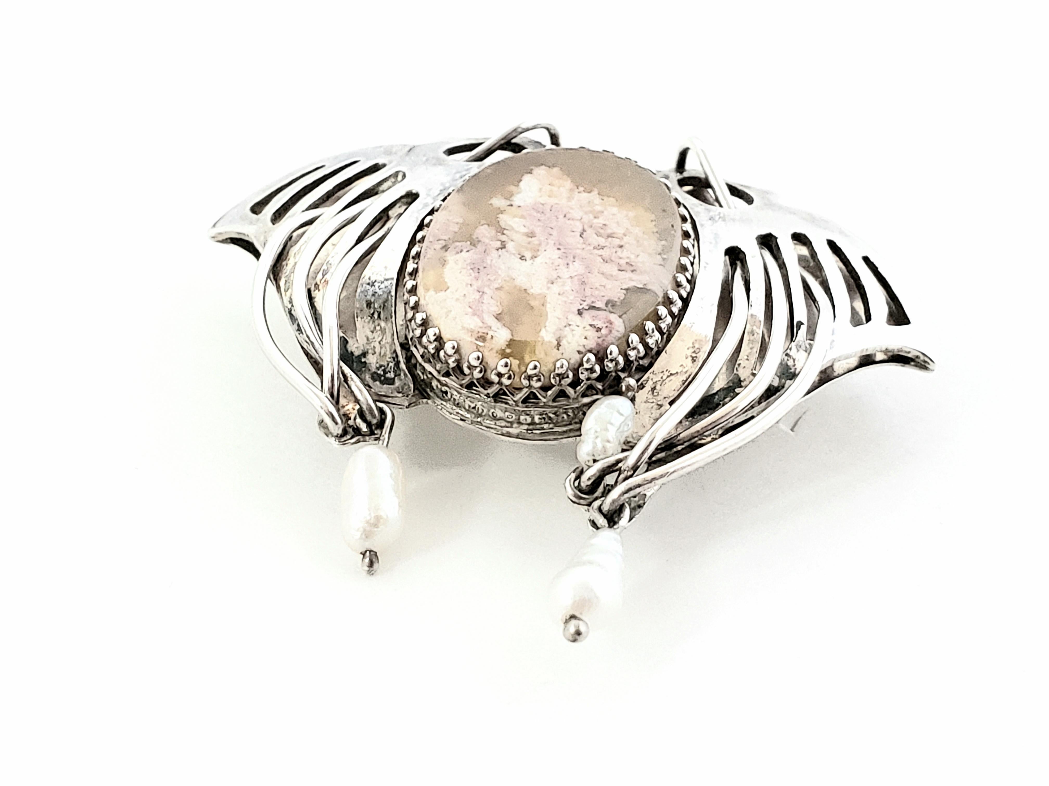 Colgante artesanal de plata de ley con ágata Laguna Lace y perla en forma de ala

Este precioso colgante artesanal de ágata Laguna Lace en forma de ala está engastado en plata de ley y acentuado con perlas. El colgante grita hecho a mano y único