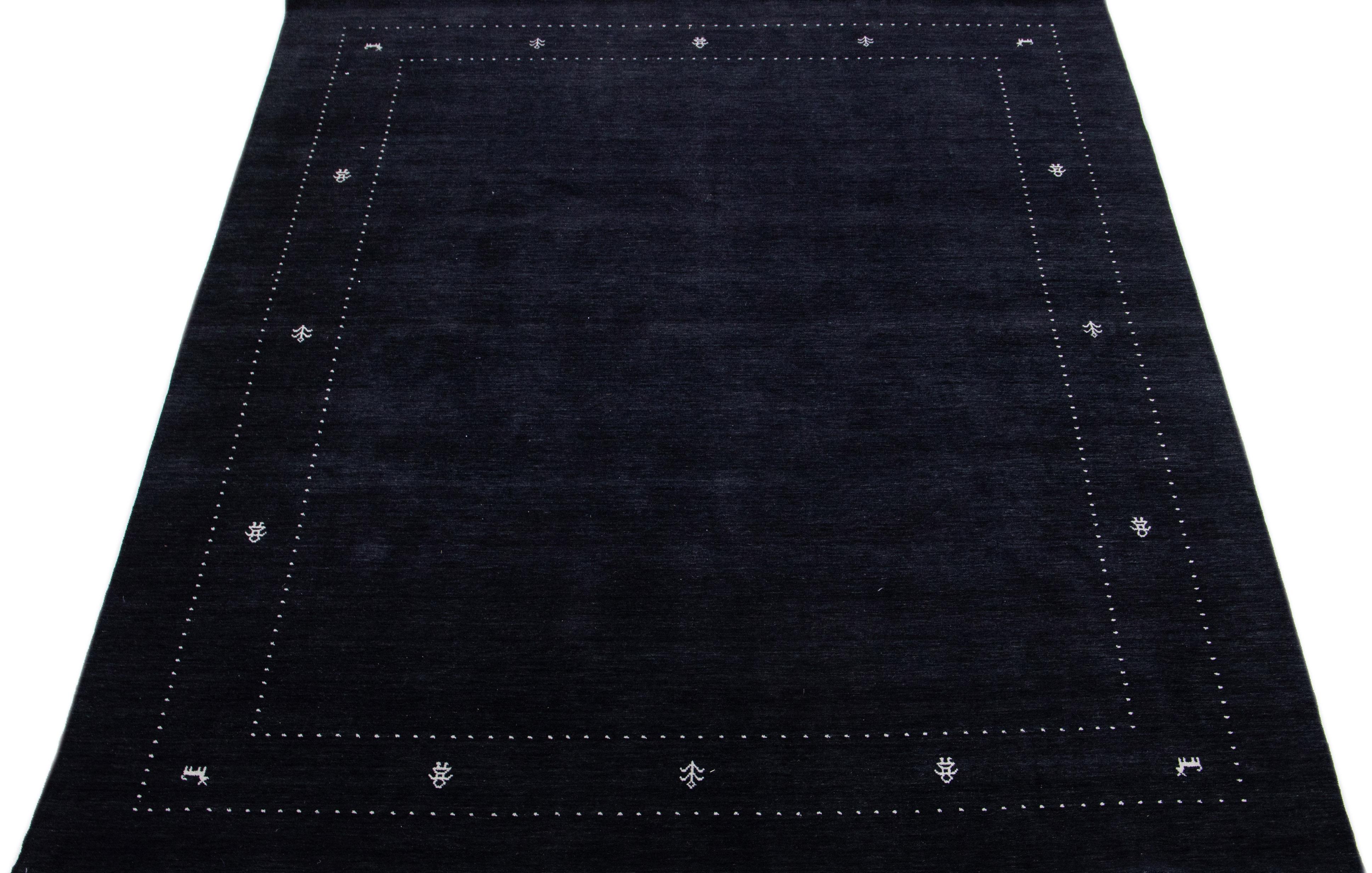 Caratterizzato da un moderno design in stile Gabbeh, questo tappeto in lana intrecciata a mano presenta un campo di colore nero e accenti bianchi dall'eleganza classica.

Questo tappeto misura: 9' x 11.10
