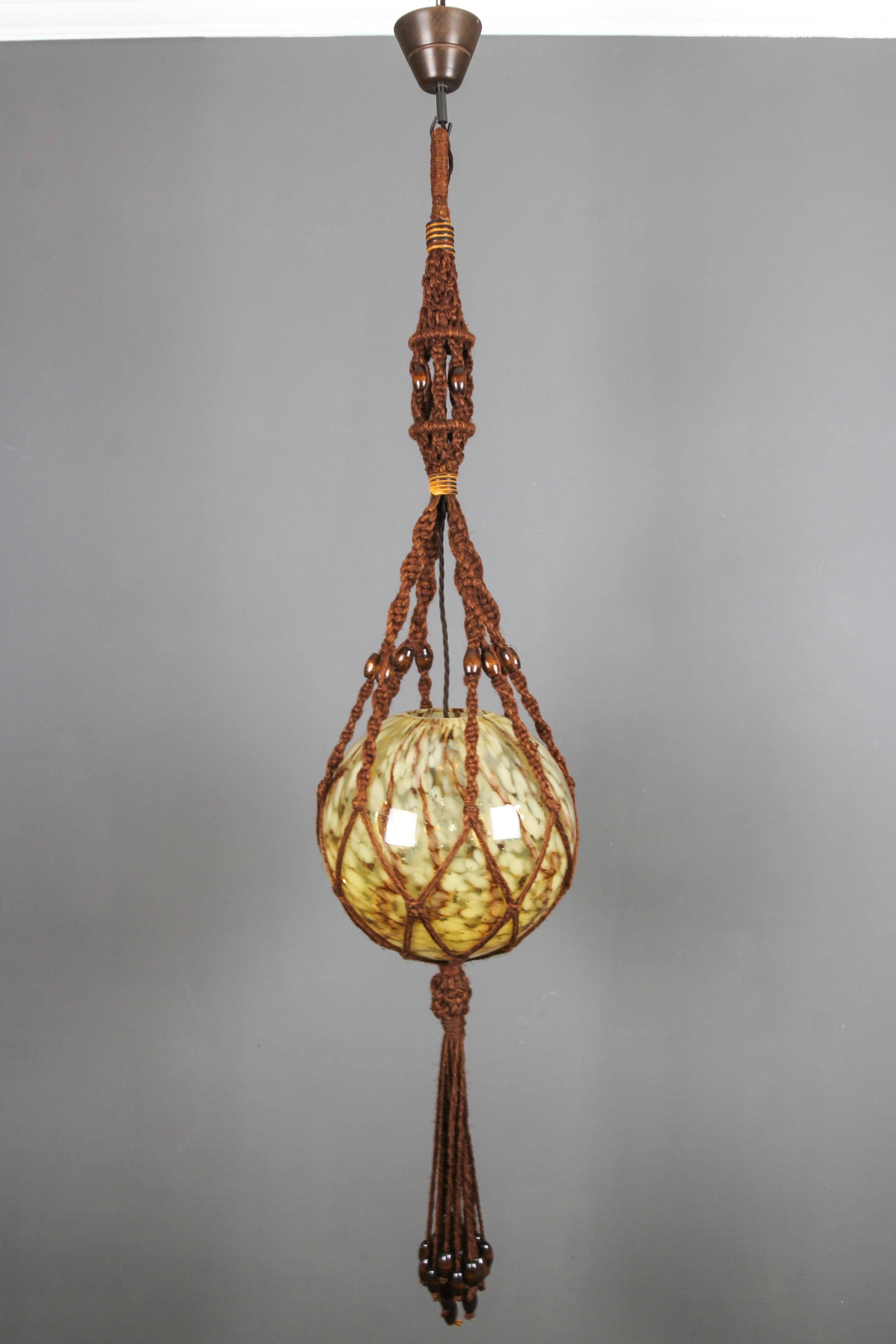 Unique hand-crafted vintage pendant light fixture from circa the 1970s. This unusual braided pendant lamp is handmade of brown sisal/jute and decorated with wooden beads; a brown and beige marbled glass globe lampshade is in the center of the light