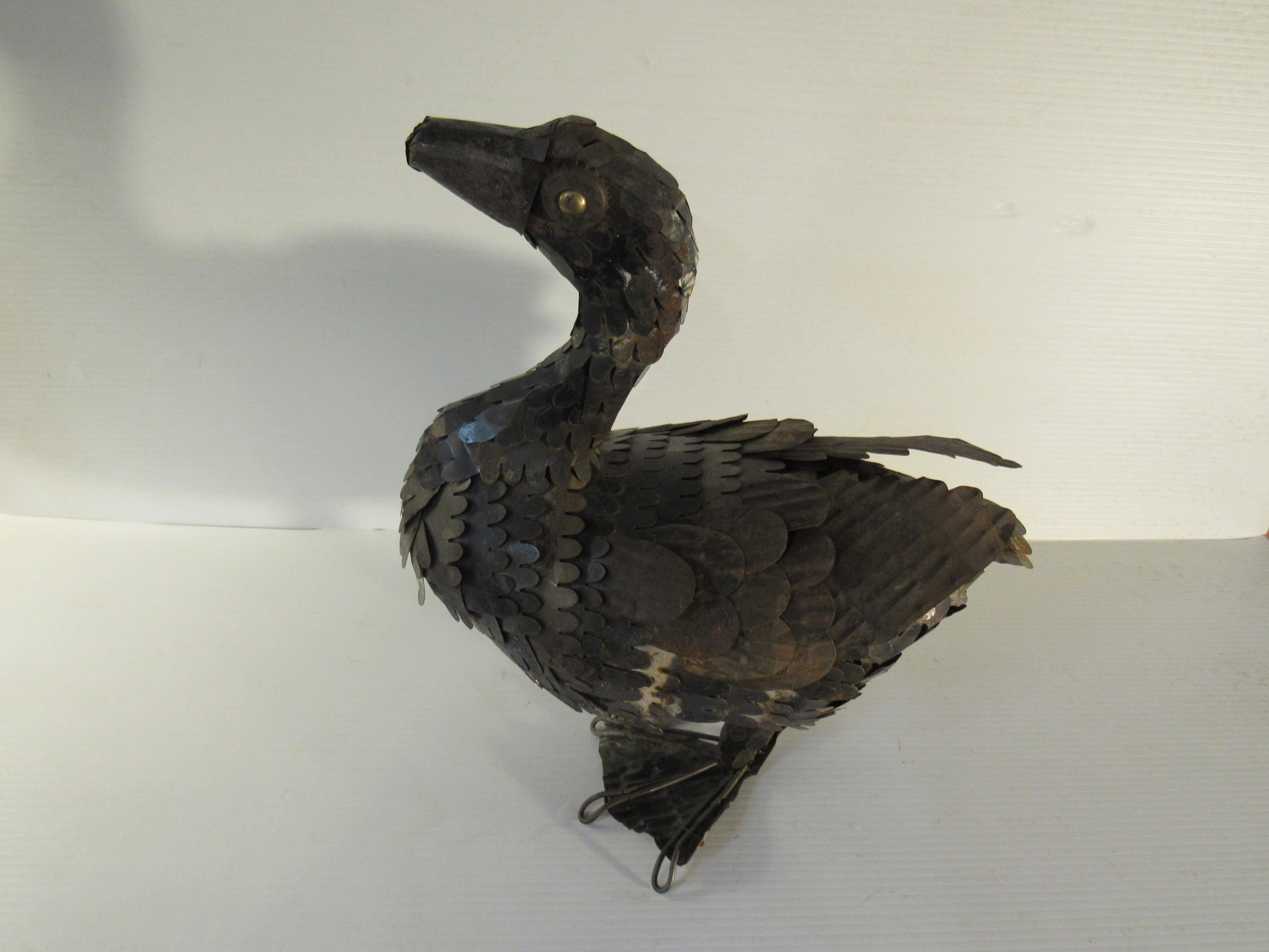 Whether it's a goose or a duck, or some other waterfowl this handmade metal bird is sure to make a splash in any space. Layers of cut and welded sheet metal give a wonderful lifelike effect to the feathers while bottlecap eyes add to the vintage