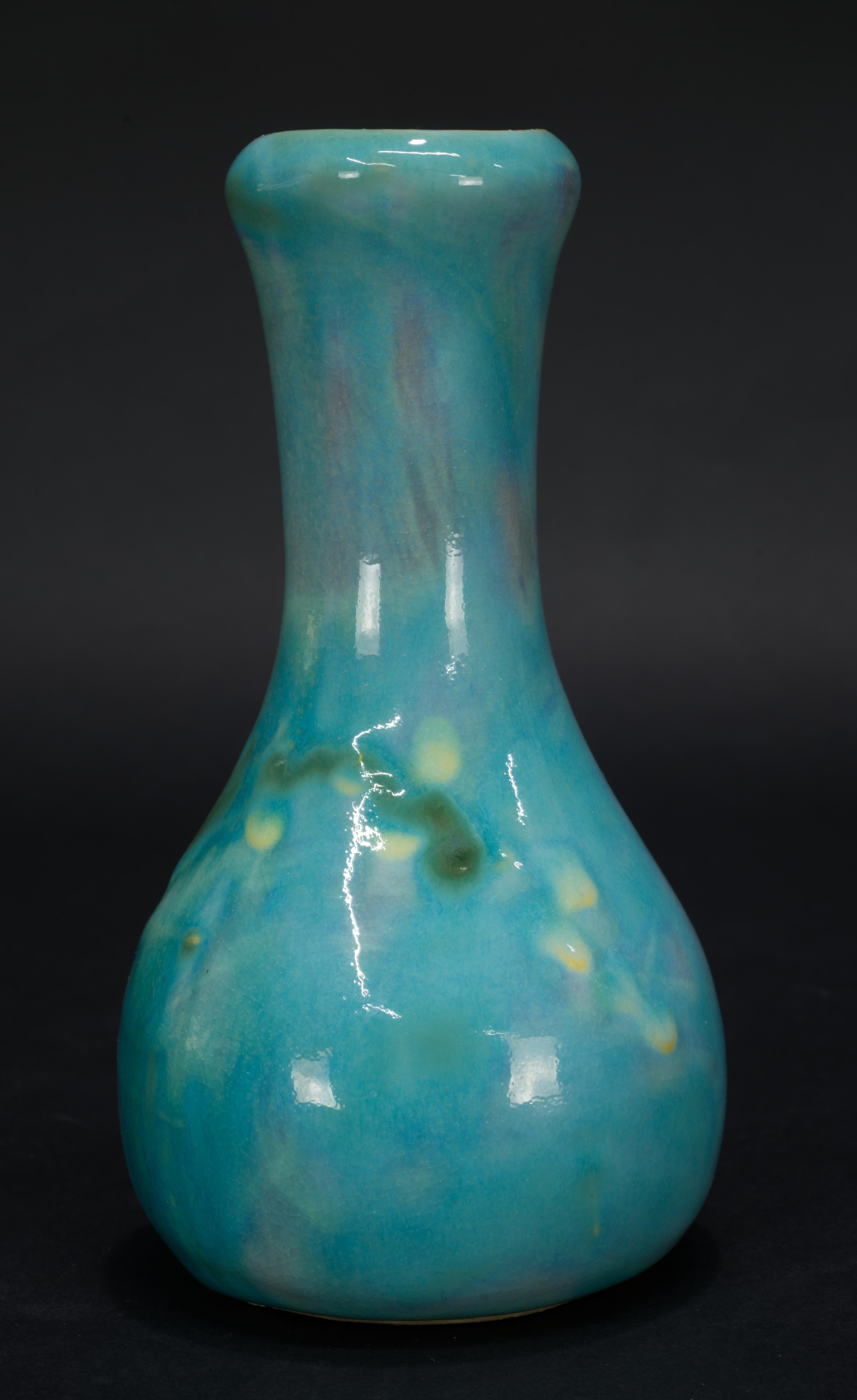  Whimsical and cheerful bud vase was handmade by Earthwork, an art pottery studio in Barbados. The vase is decorated with bright blue glaze with tastefully layered accents of mauve pink and green; a stylized raised flower decor was done with dark