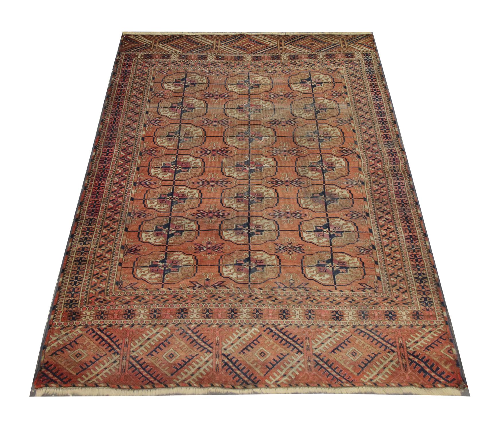 This wool rug is a great example of Bukhara rugs woven in the 1890s. The design features a repeating motif design woven on a rust-orange background with accents of beige, red and blue that make up the medallions through the centre and the repeating