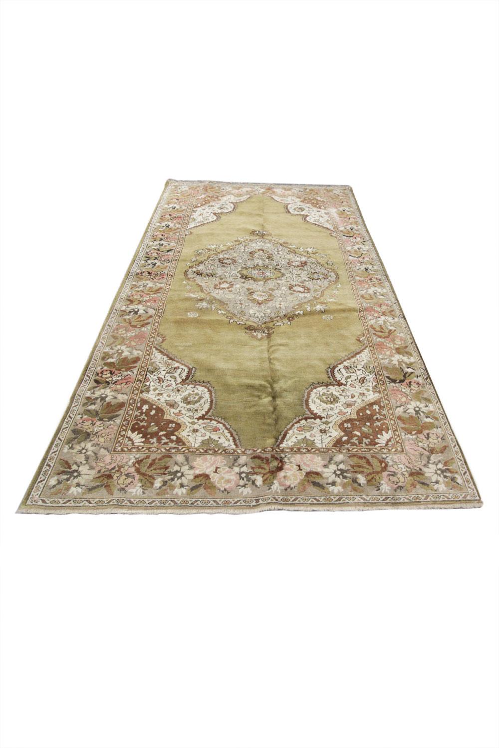 Handmade carpet muted tones of olive green, pink and beige sit in harmony on this large area rug. Handwoven with the finest handspun cotton and wool, which is dyed using organic vegetable dyes. A large central medallion makes this handmade rug stand