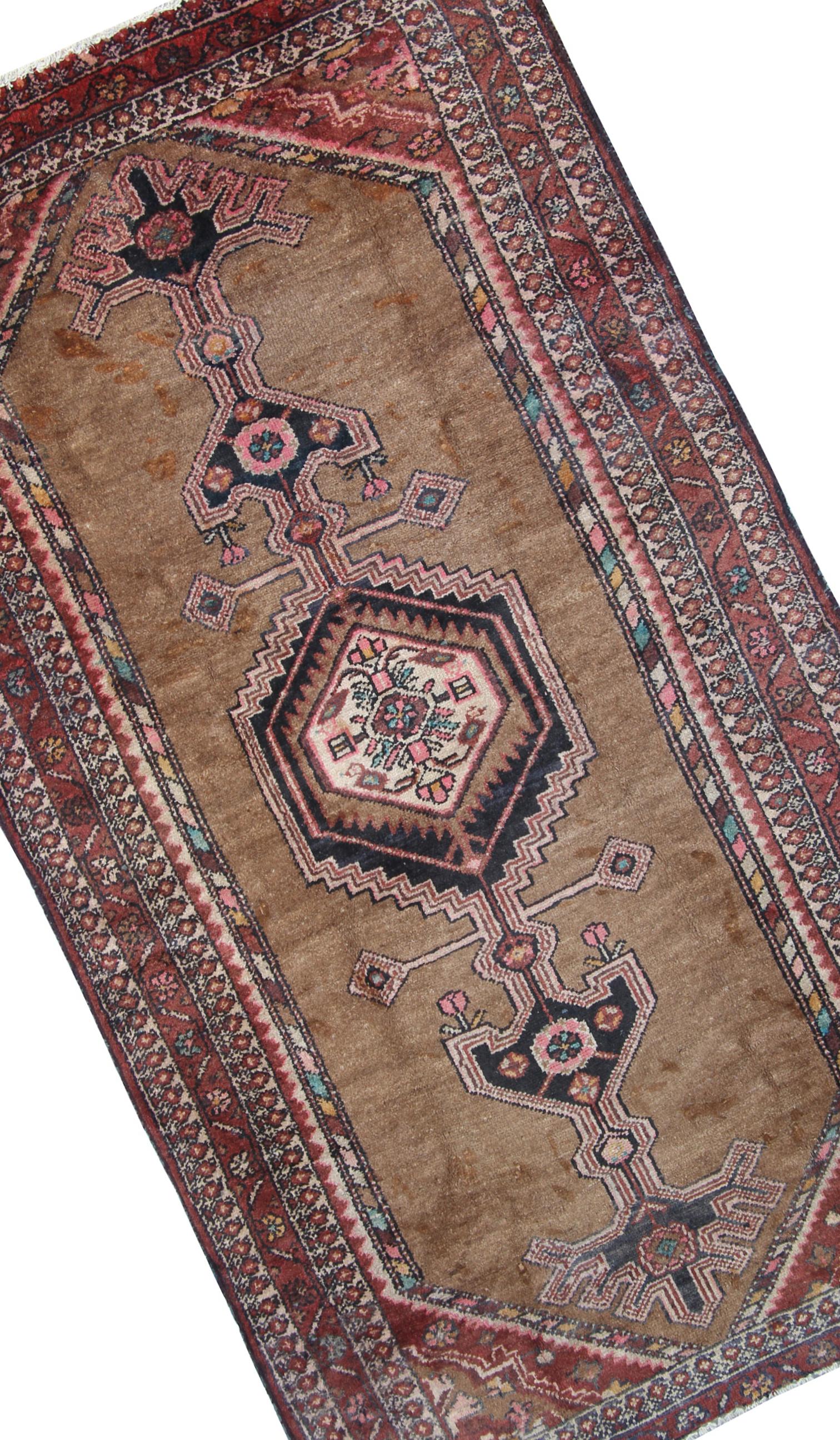 This fine wool rug was woven by hand in the 1980s. The central design features tribal medallions with geometric and floral accents throughout. Woven on a brown background with blue, brown and pink accents, with a layered brown border that frames and