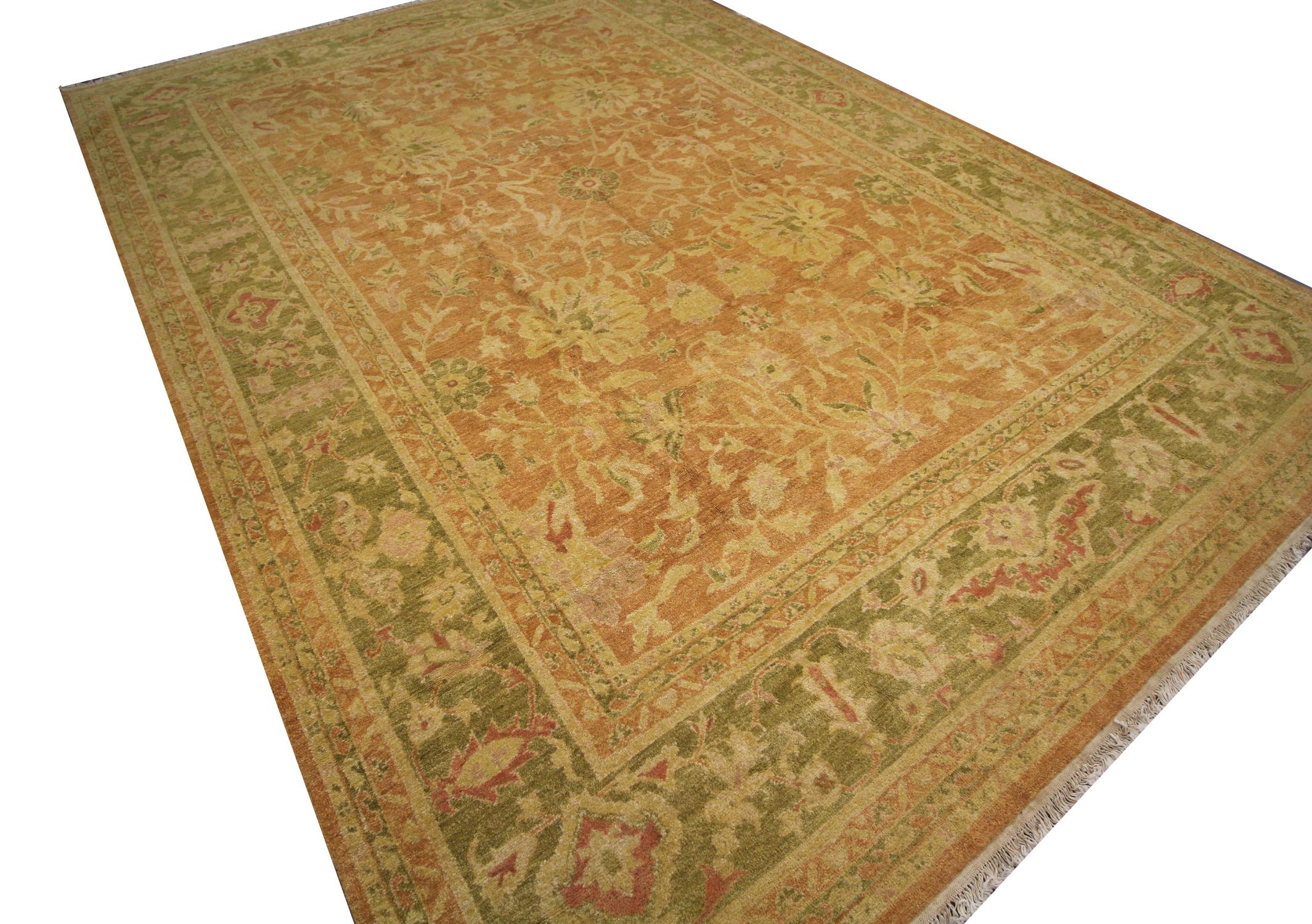 This bold over size wool area rug is a vintage Ziegler style Indian rug woven by hand in the 1990s. The floral design is a traditional Ziegler style woven on a rust-beige background with green and cream accents. The symmetrical floral pattern and