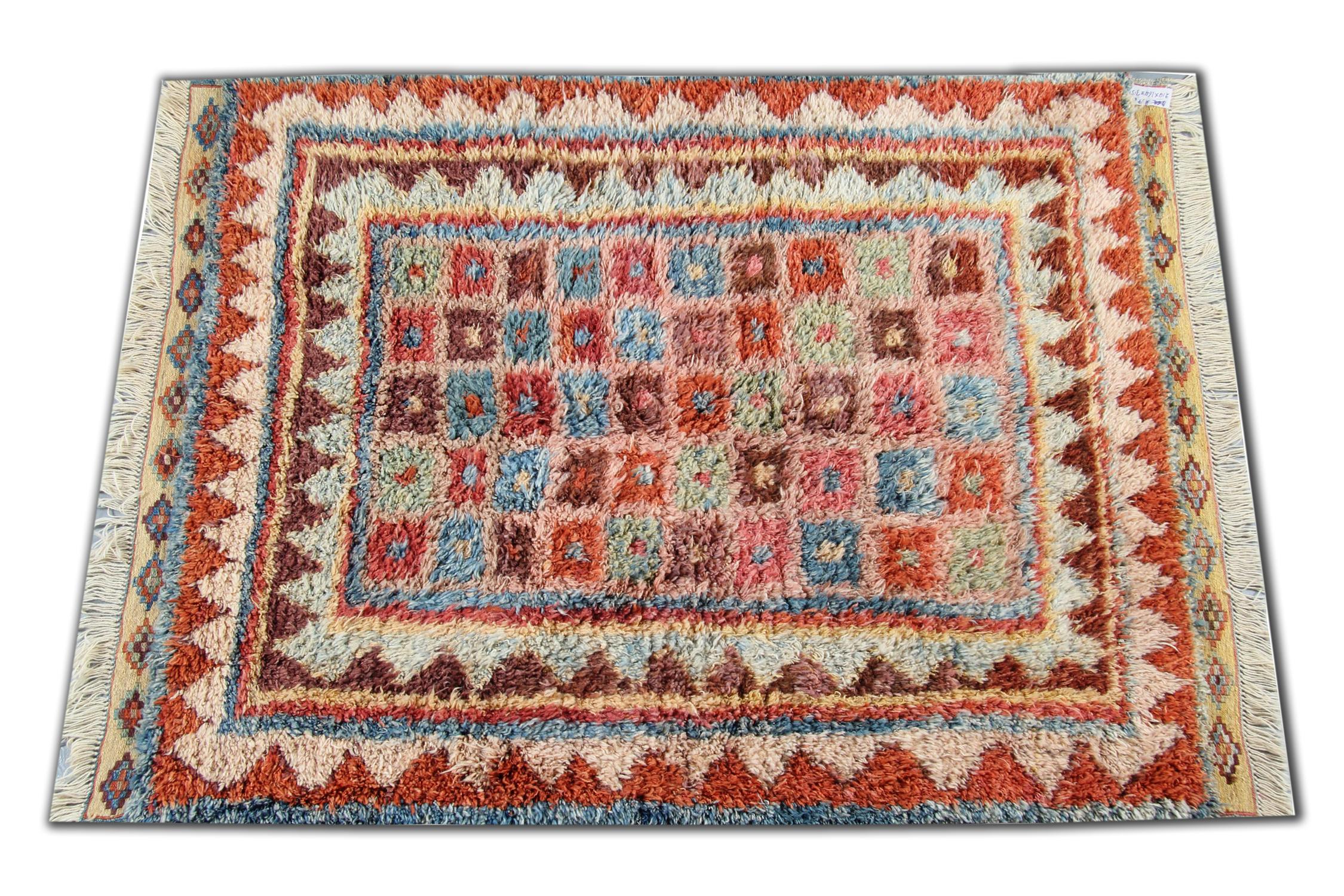 This handmade carpet is an example of a handwoven rug, which features designs from the Morocco region. Morocco is famous for its primitive traditional rugs with long piles. Weavers used top-quality wool and cotton for the production of this red rug.