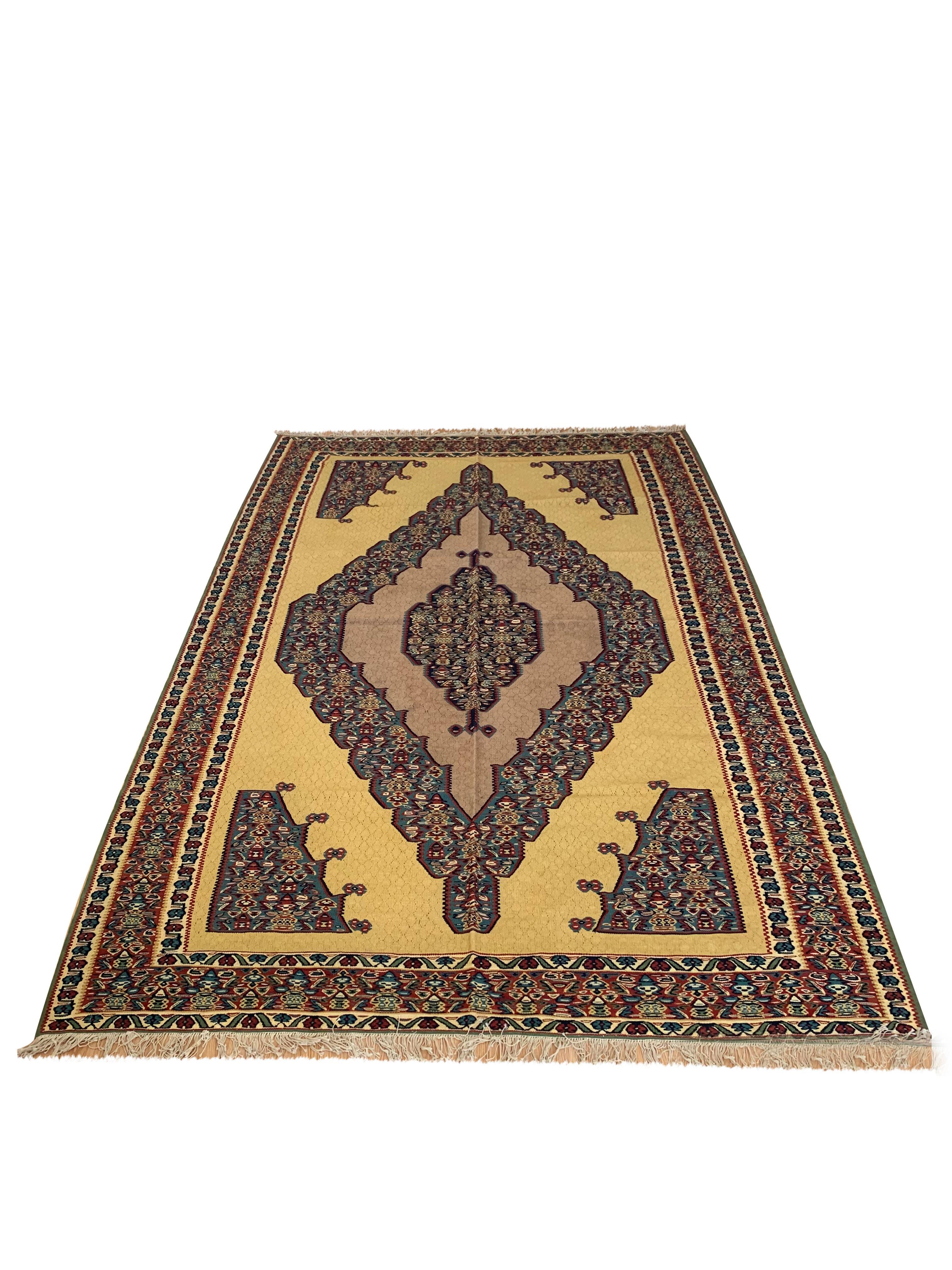 This beautiful wool carpet is a handmade, flatwoven kilim woven in the early 21st century, circa 2010. It is unused and so is in excellent condition. The design features a bold medallion design woven on a yellow background with blue, red and cream