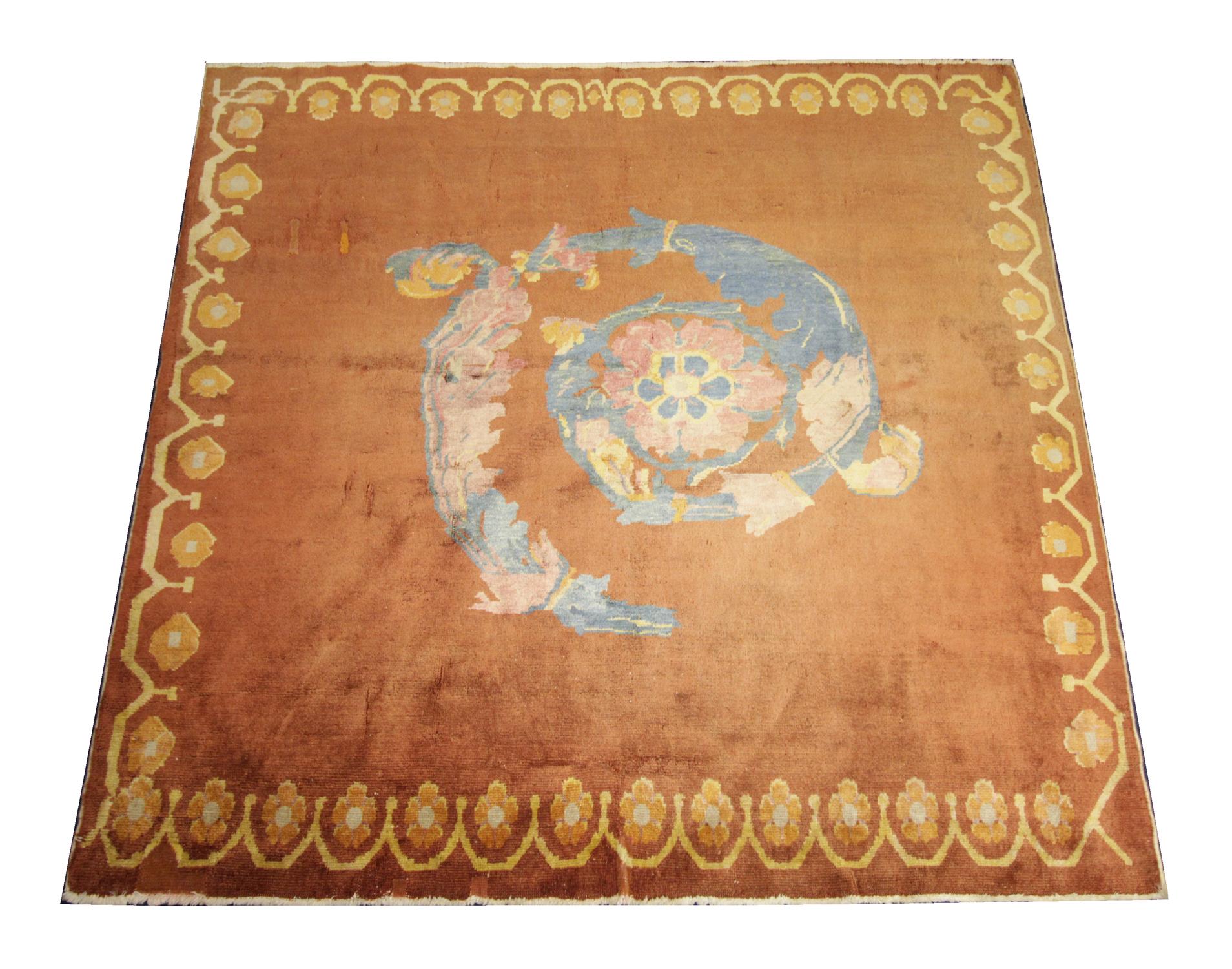 This fine wool rug was woven by hand in the 1930s in China. The central design features an abstract swirl pattern made up of blue, pink and orange accent colours that contrast elegantly with the orange background. This has then been framed by a