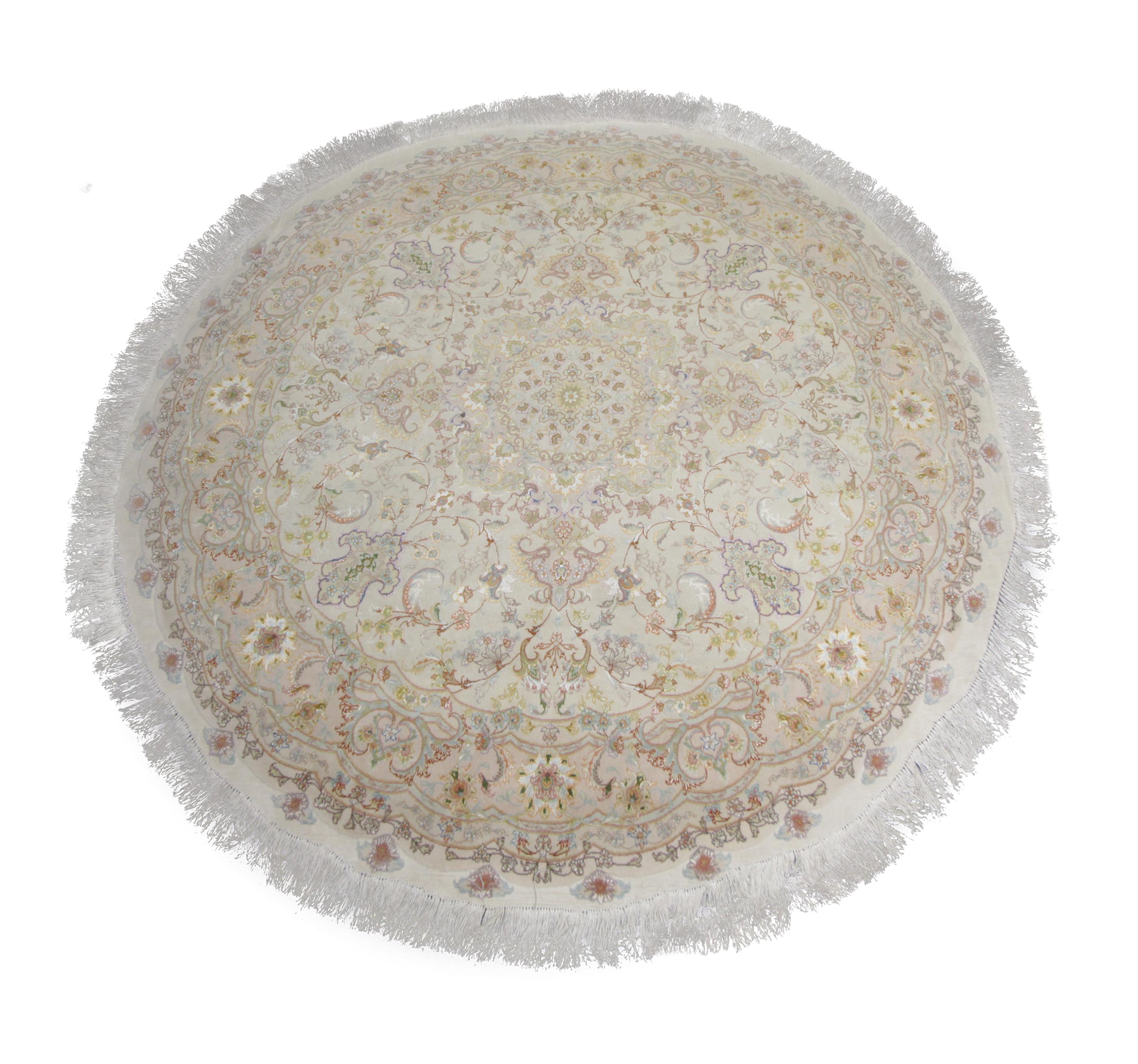 This small circular wool rug was woven by hand in Turkey in the early 2000s with fine organic materials. The design features a cream background with accents of pink, ivory, blue and green that make up the intricate symmetrical medallion design. This