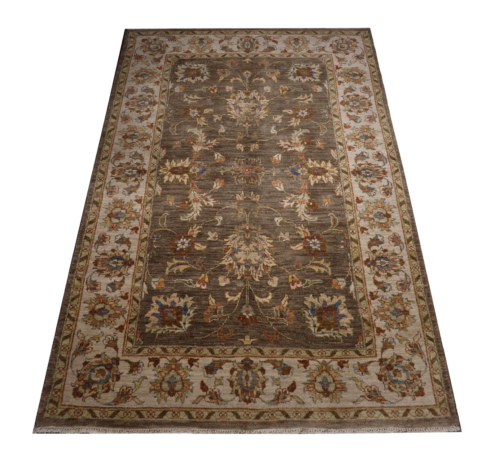 This vintage carpet is an Indian Ziegler rug woven by hand with fine wool and cotton. The design has been woven with a luxurious brown background with accents of cream, beige and orange that make up the symmetrical floral design. The traditional