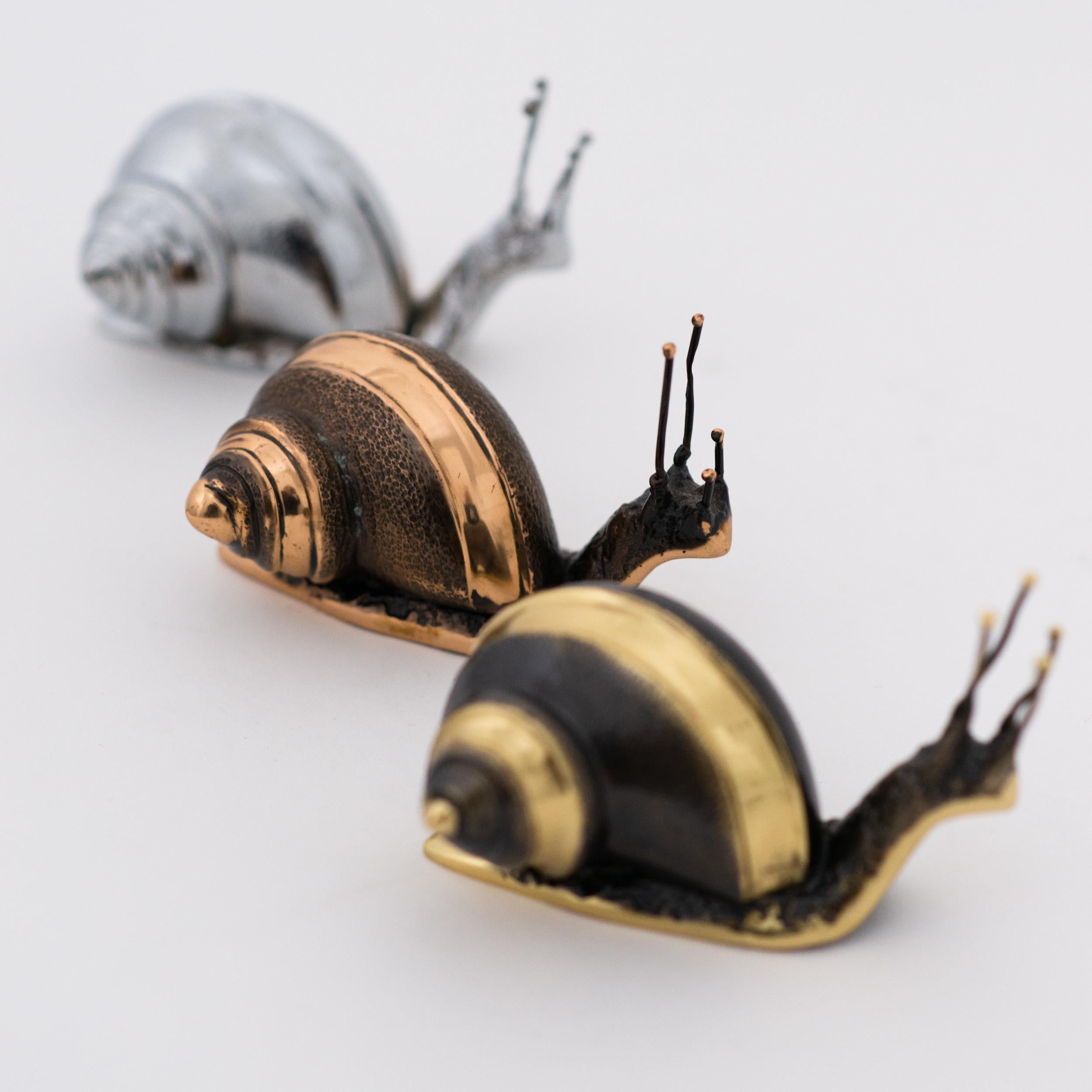 Chacun de ces exquis escargots en bronze massif est fabriqué à la main, individuellement, avec un niveau de détail incroyable. Coulée selon des techniques très traditionnelles, la matière noble est vieillie en dévoilant une belle patine et finie par
