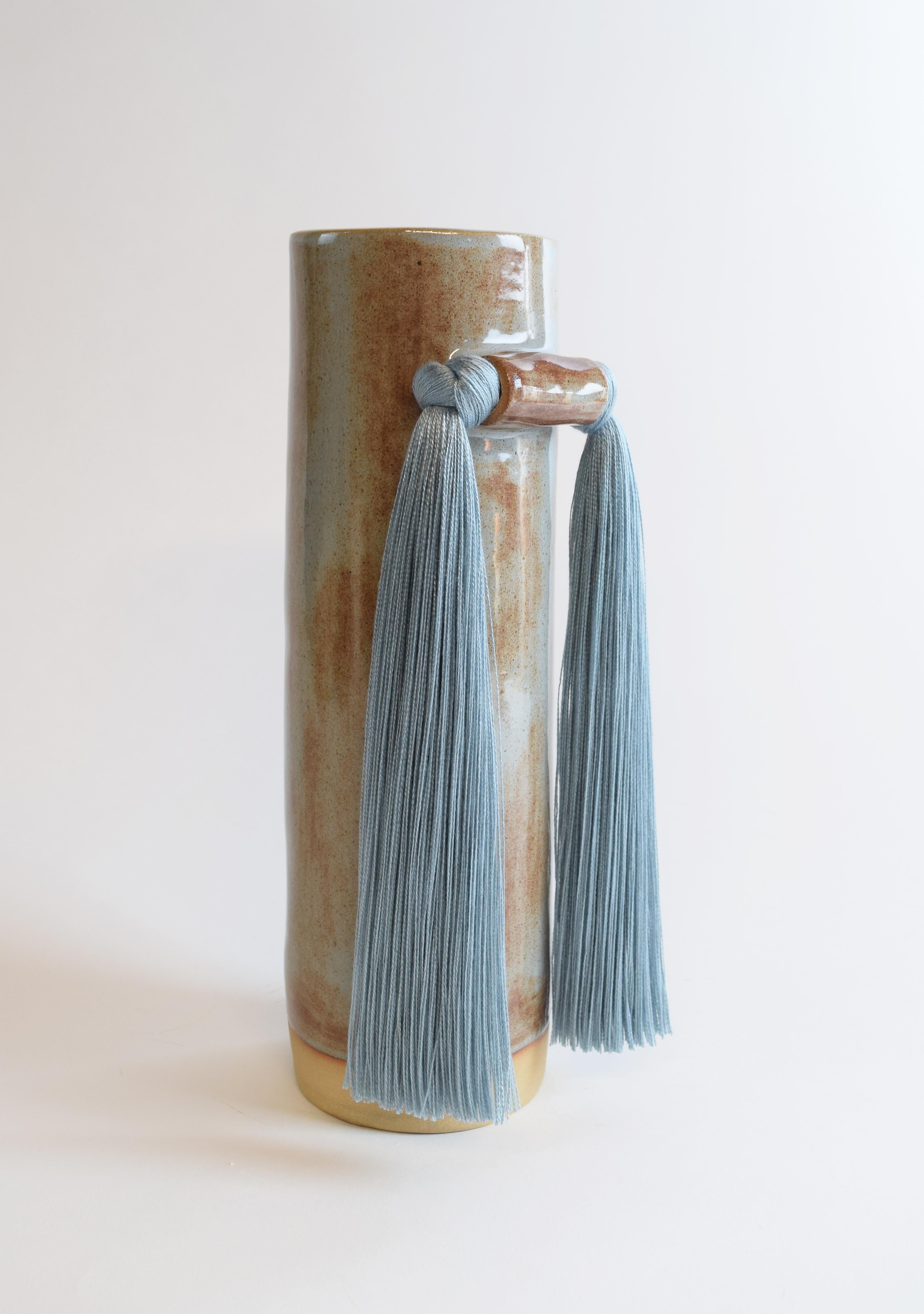 Vase #531 by Karen Gayle Tinney

Quiet symmetry and front-facing fringe details make this vase perfect for display on a shelf or table.

Hand formed beige stoneware with blue shino glaze. Blue tencel fringe detail. Inside is glazed white, vessel