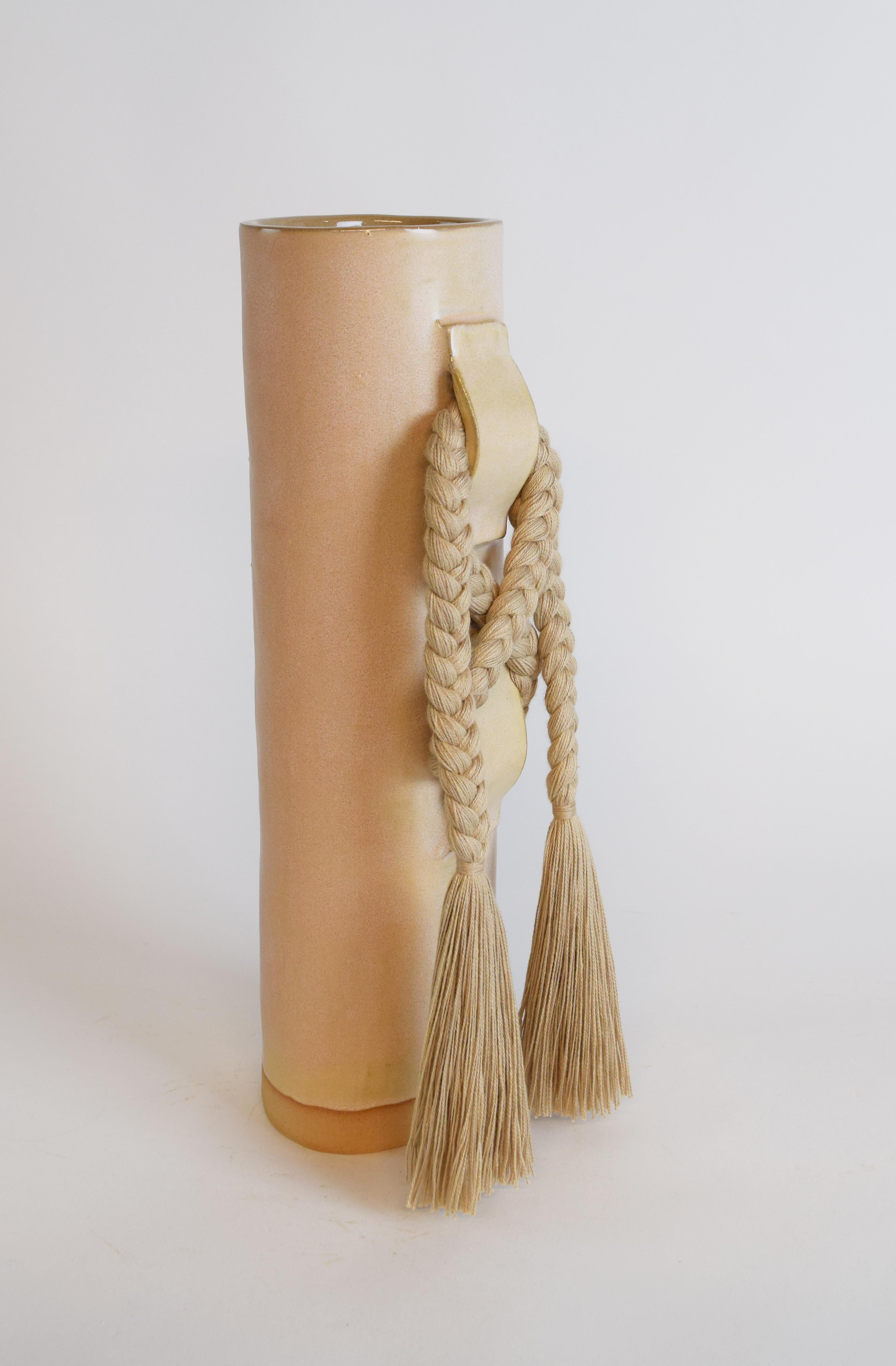 Vase #696 by Karen Gayle Tinney

Featuring a large gestural knot, this vase takes inspiration from the braided details of Karen’s one of a kind wall sculptures.

Hand formed stoneware with satin tan glaze. Tan cotton braided details (braid is sewn