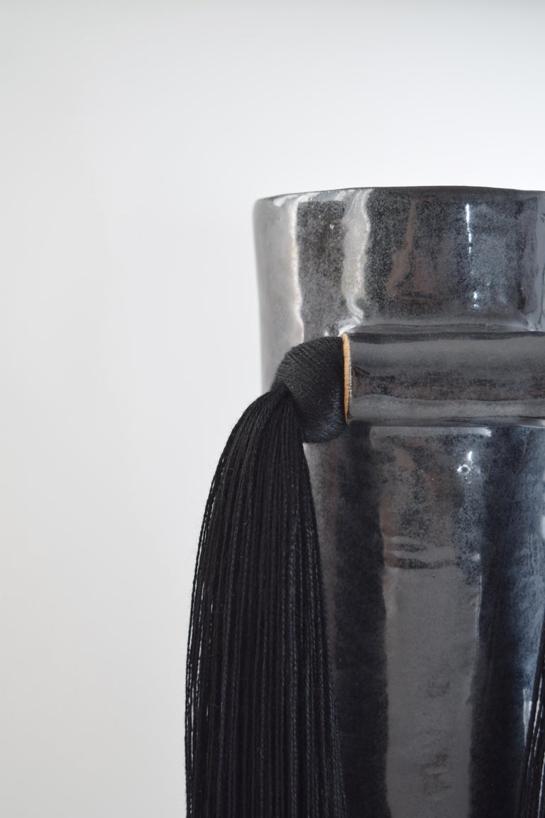 Vase #531 by Karen Gayle Tinney.

Hand formed stoneware vase glazed in a shiny black color. Inside is glazed black and will hold water, please take care not to damage fringe areas. Black tencel fringe is applied on the outside of the vase. This vase