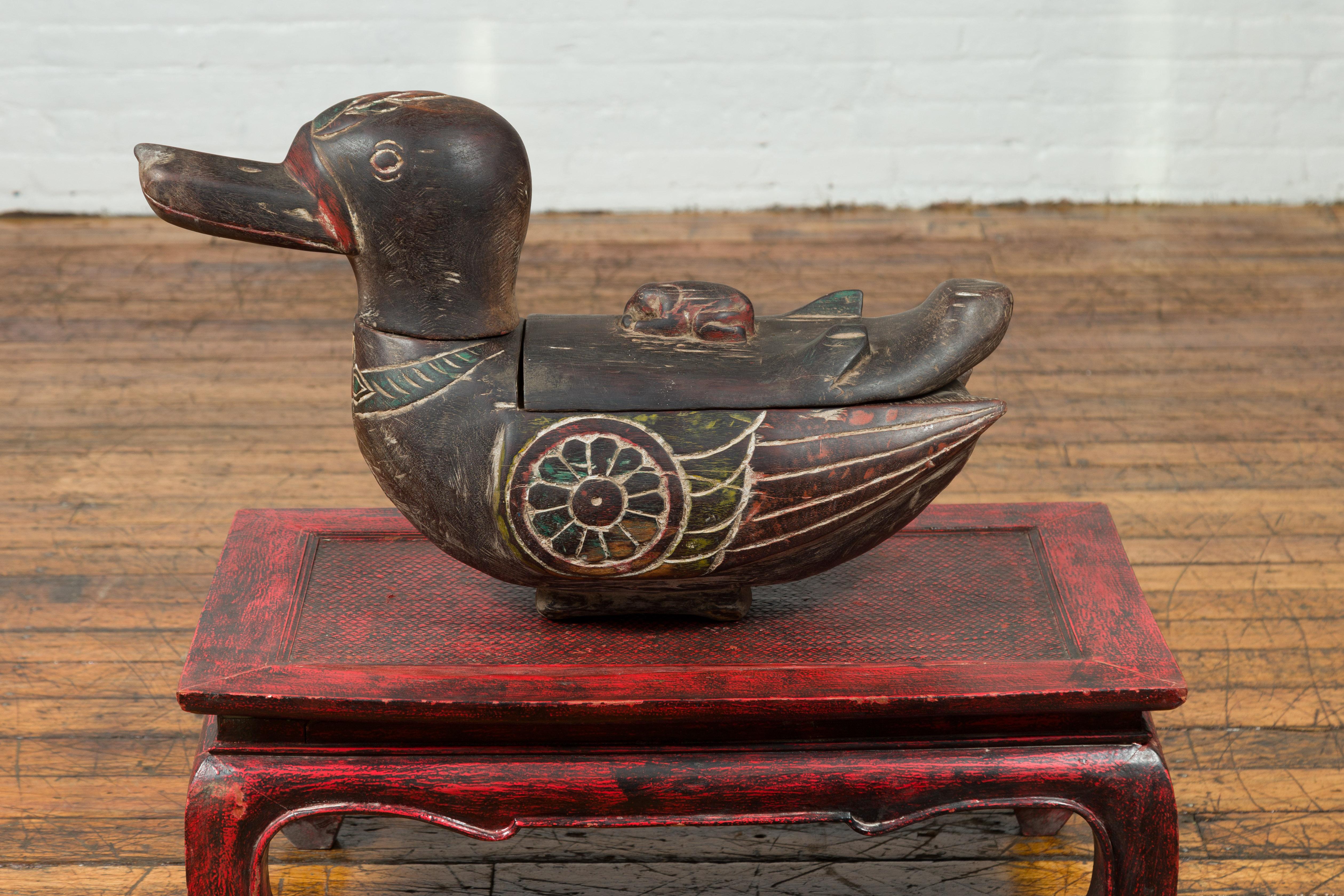 A contemporary Thai handmade duck prayer box with polychrome accents, found in Chiang Mai. Created in Northern Thailand, this hand carved wooden prayer box depicts a small duck with removable top, accented with red and green highlights. Incised on