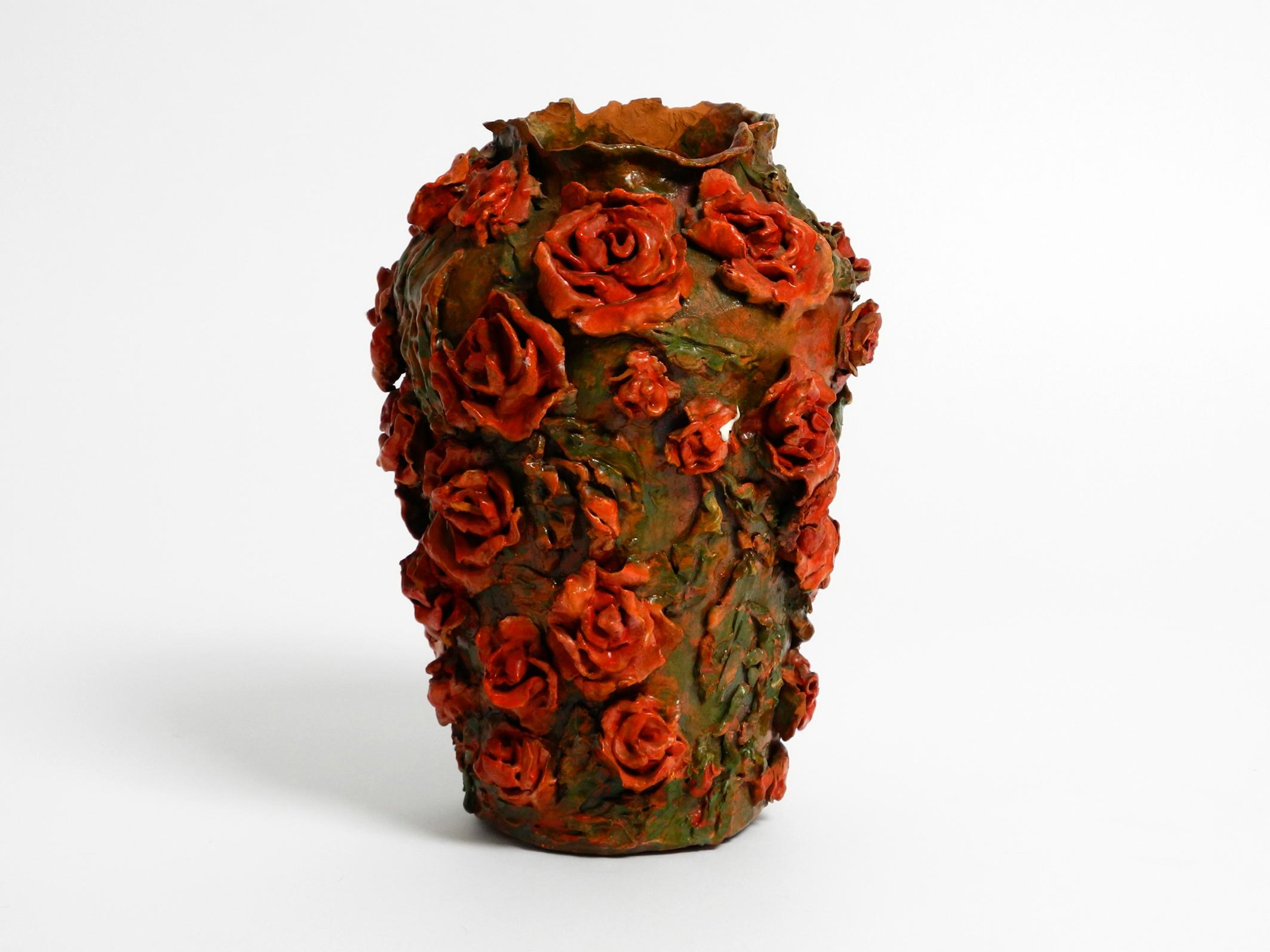 Very beautiful handmade glazed clay vase in green-brown and with red roses.
Under the vase there is the name 